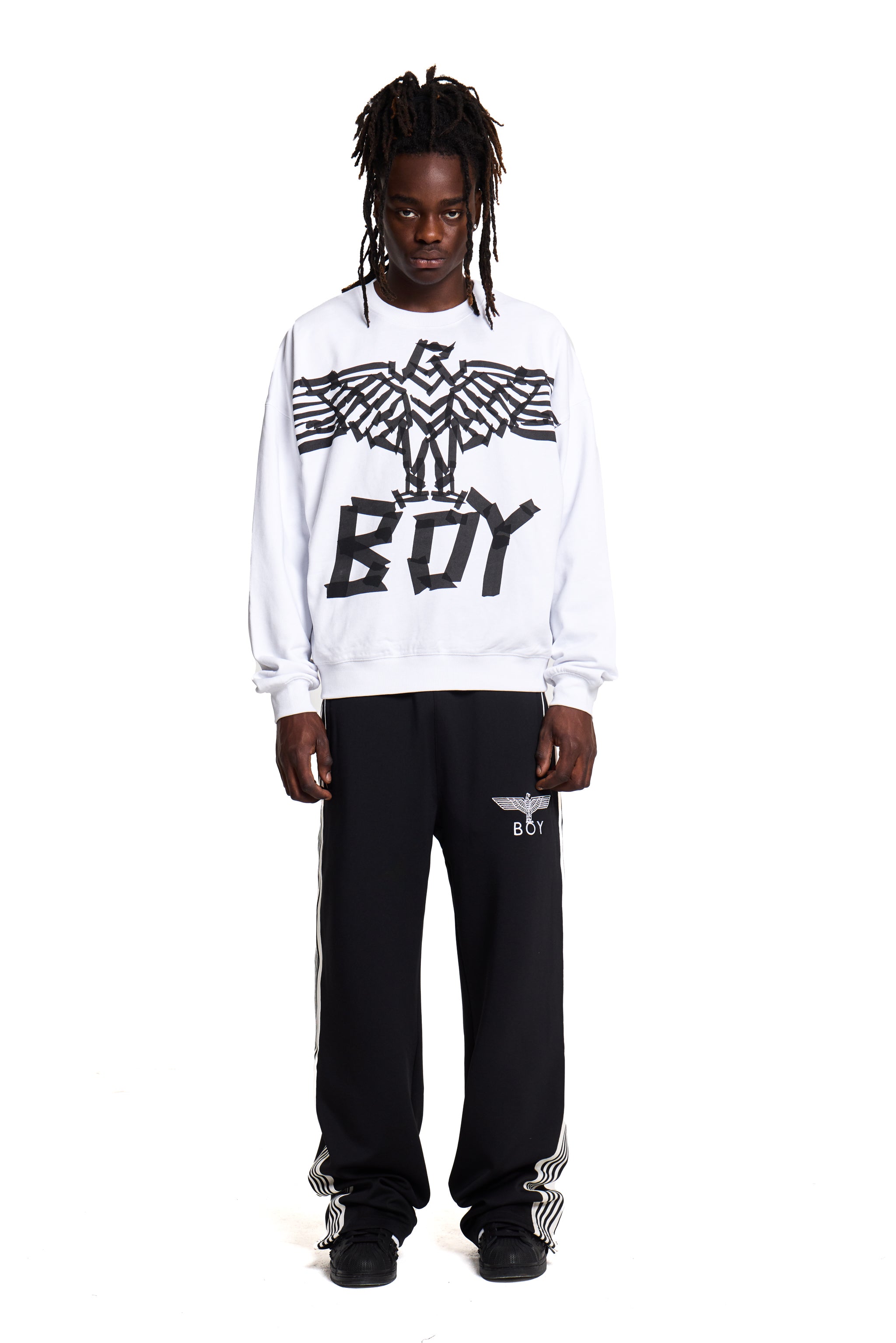 Model wearing a white sweatshirt with 'BOY' London and an eagle logo, standing against a white background