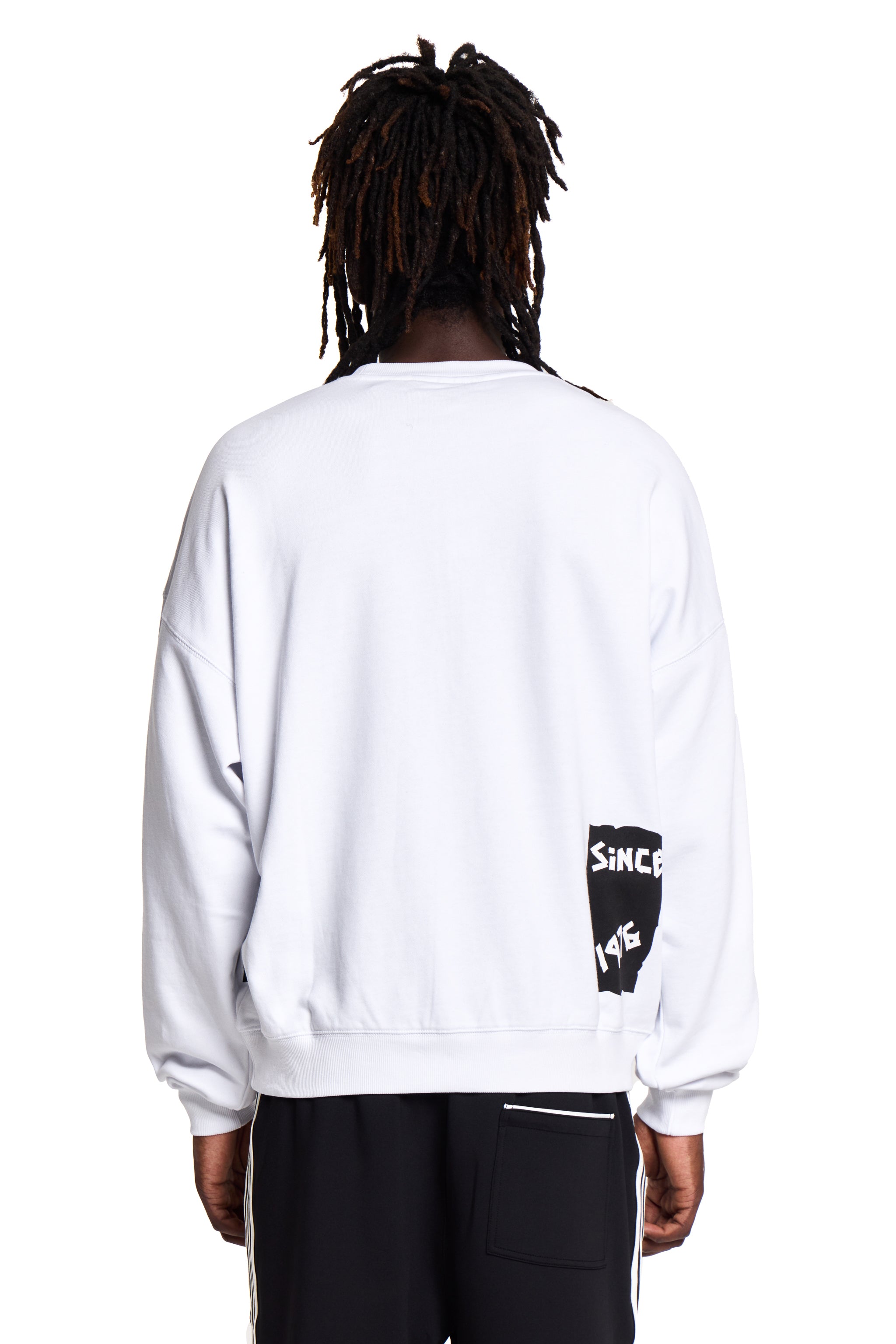 Model wearing a white BOY London sweatshirt with a logo on the back, standing against a white background