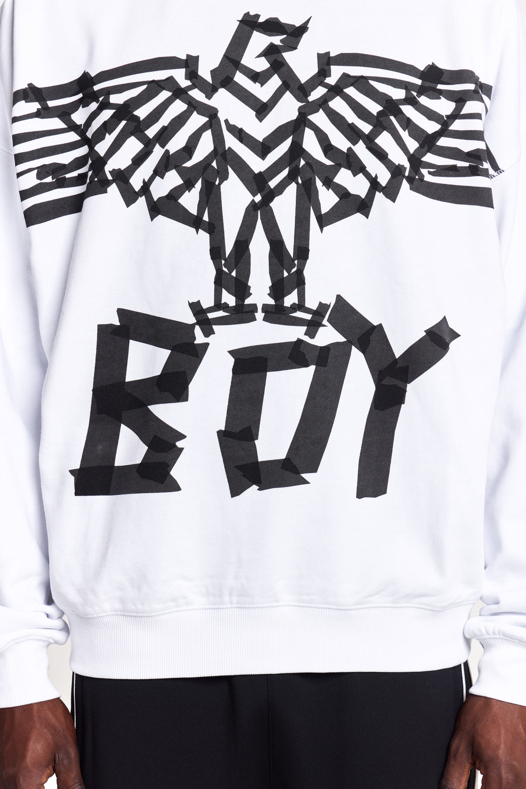 Model wearing White BOY London sweatshirt with black abstract design and 'BOY' text on a white background