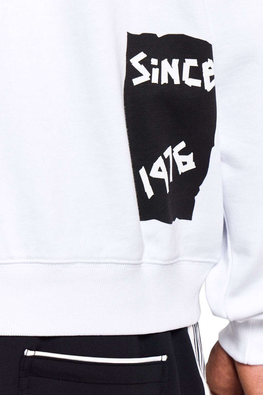 Model wearing White BOY London sweatshirt with black arm sleeve displaying 'SINCE 1976' on a white background