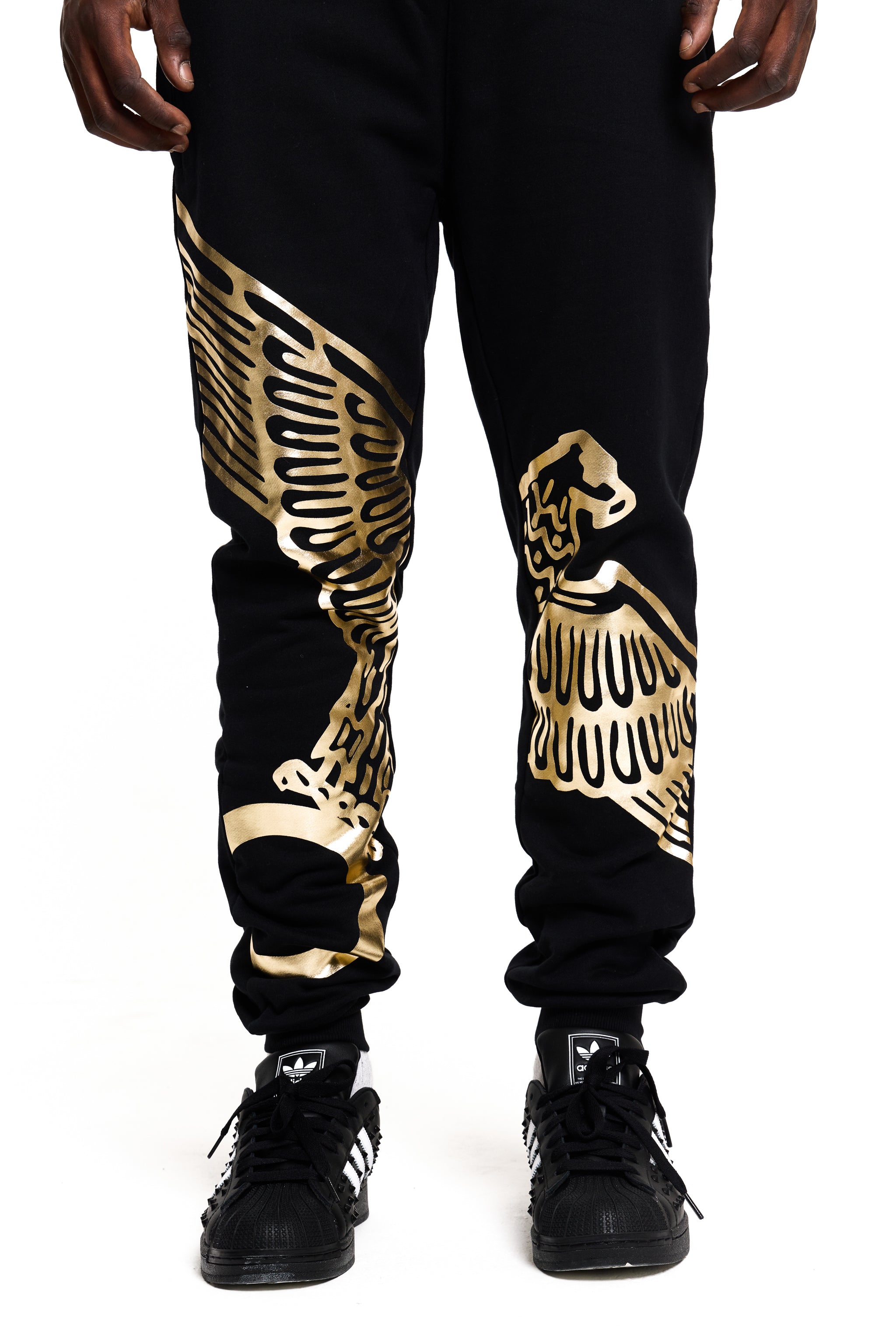 Black BOY London jogger pants with gold eagle designs worn by a person on a white background