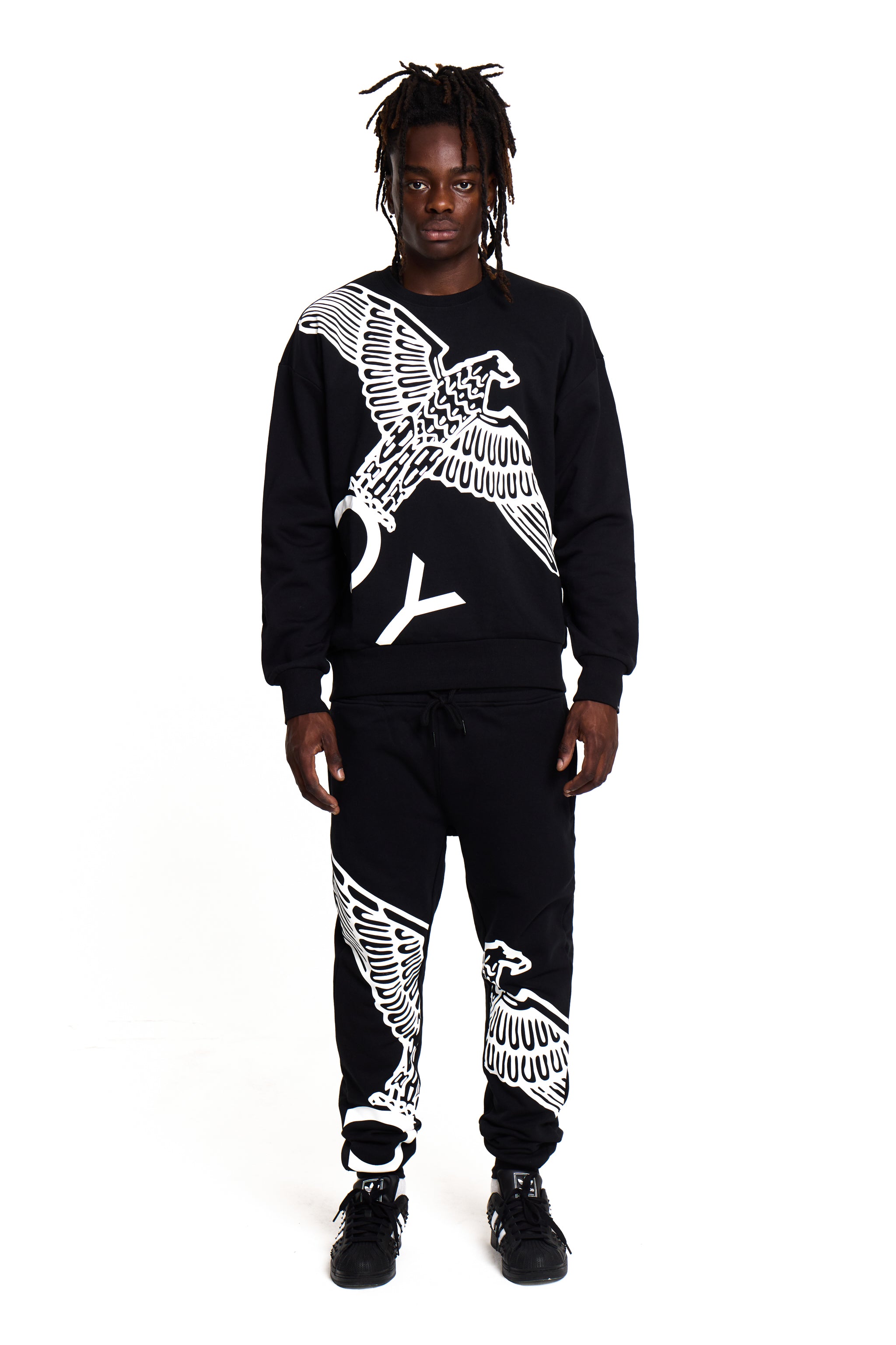 Model wearing a black BOY London tracksuit with white eagle designs on a white background