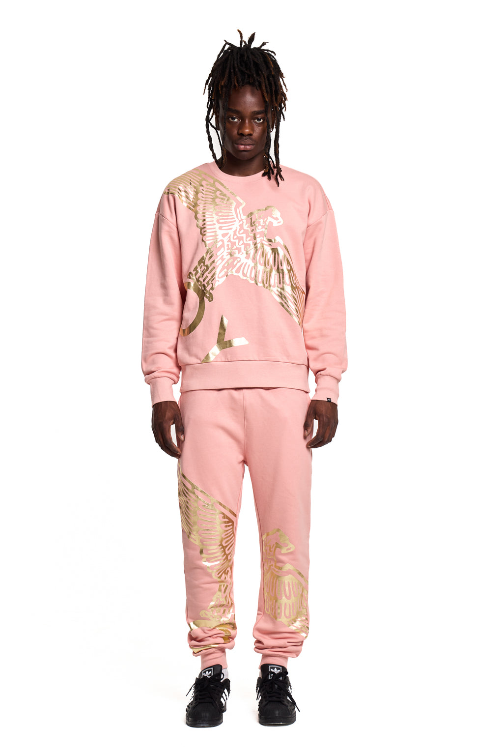 Person wearing a pink BOY London tracksuit with gold designs on a white background