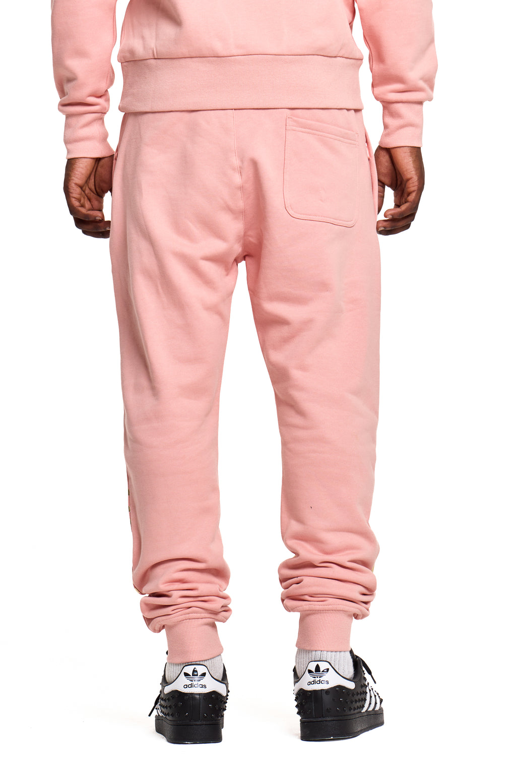 Person wearing a pink BOY London tracksuit with shoes on a white background