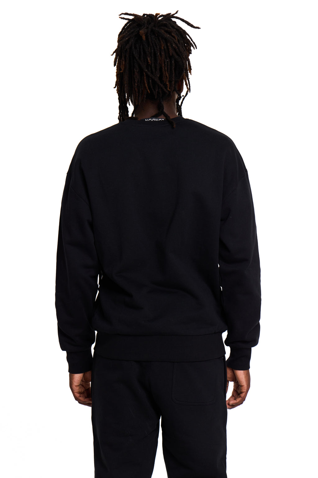 Model wearing a black BOY London tracksuit with a visible brand logo on the back against a white background