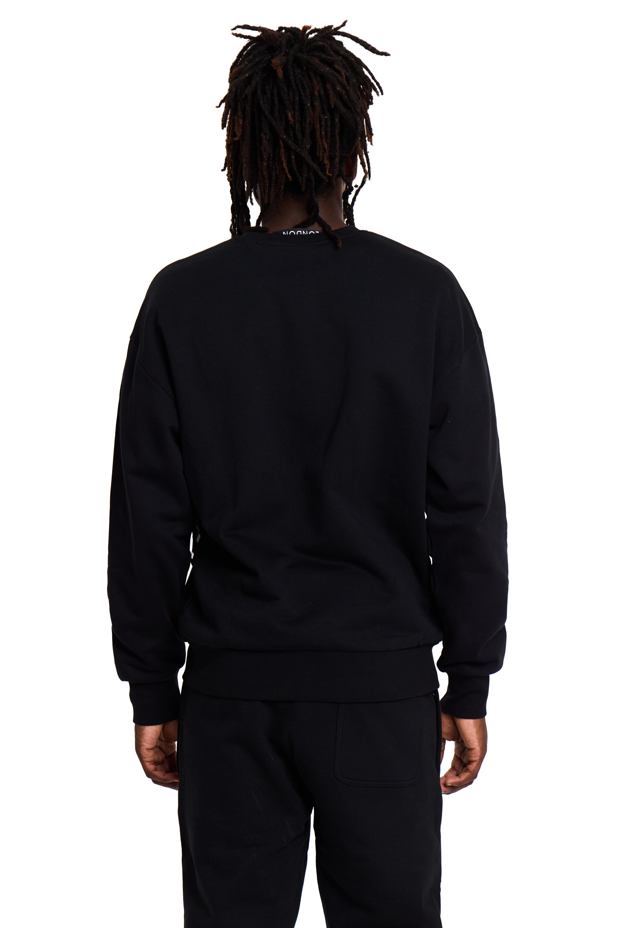 Model wearing a black BOY London tracksuit with a visible brand logo on the back against a white background