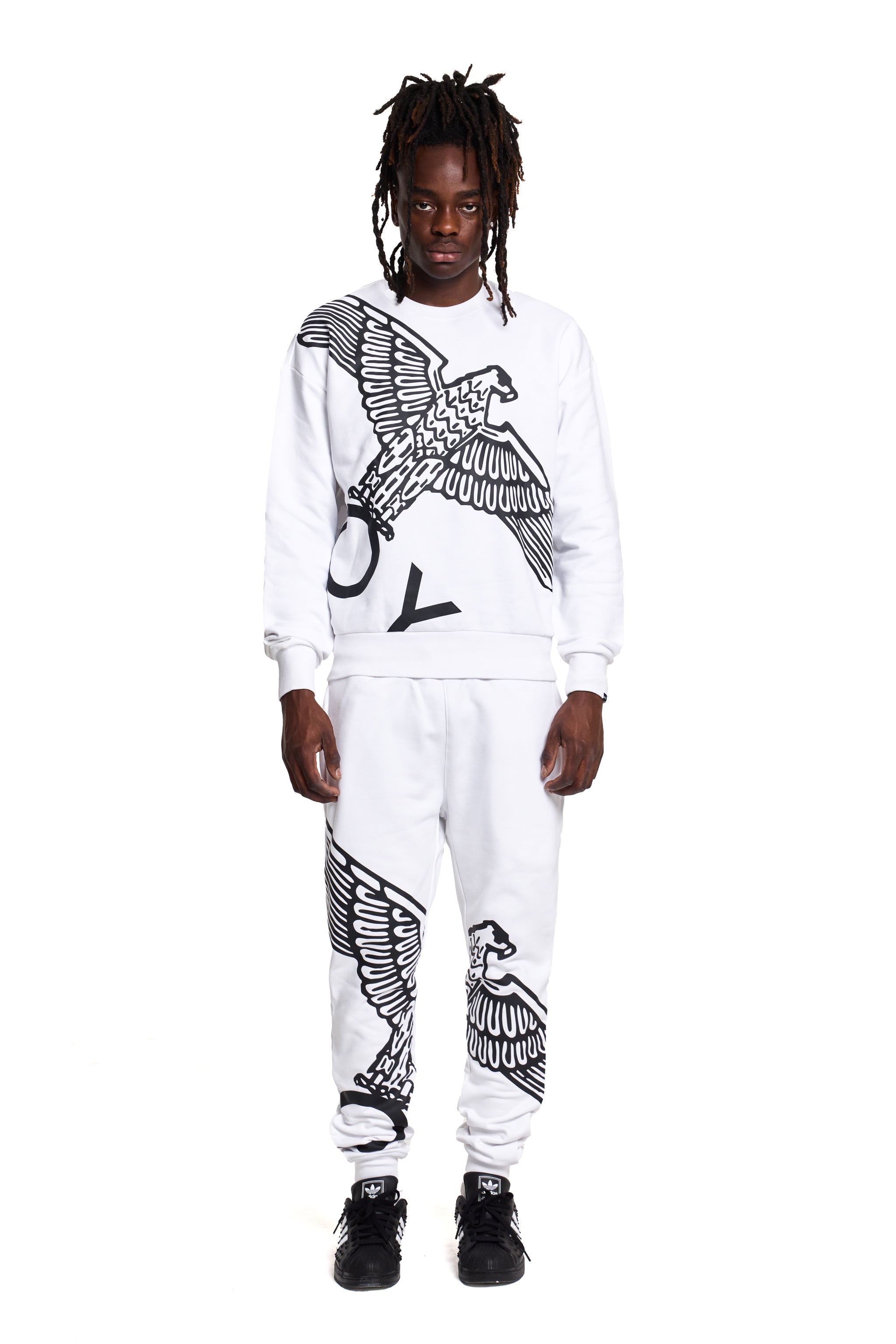 model wearing a white BOY London sweatshirt and pants with black eagle designs on a white background