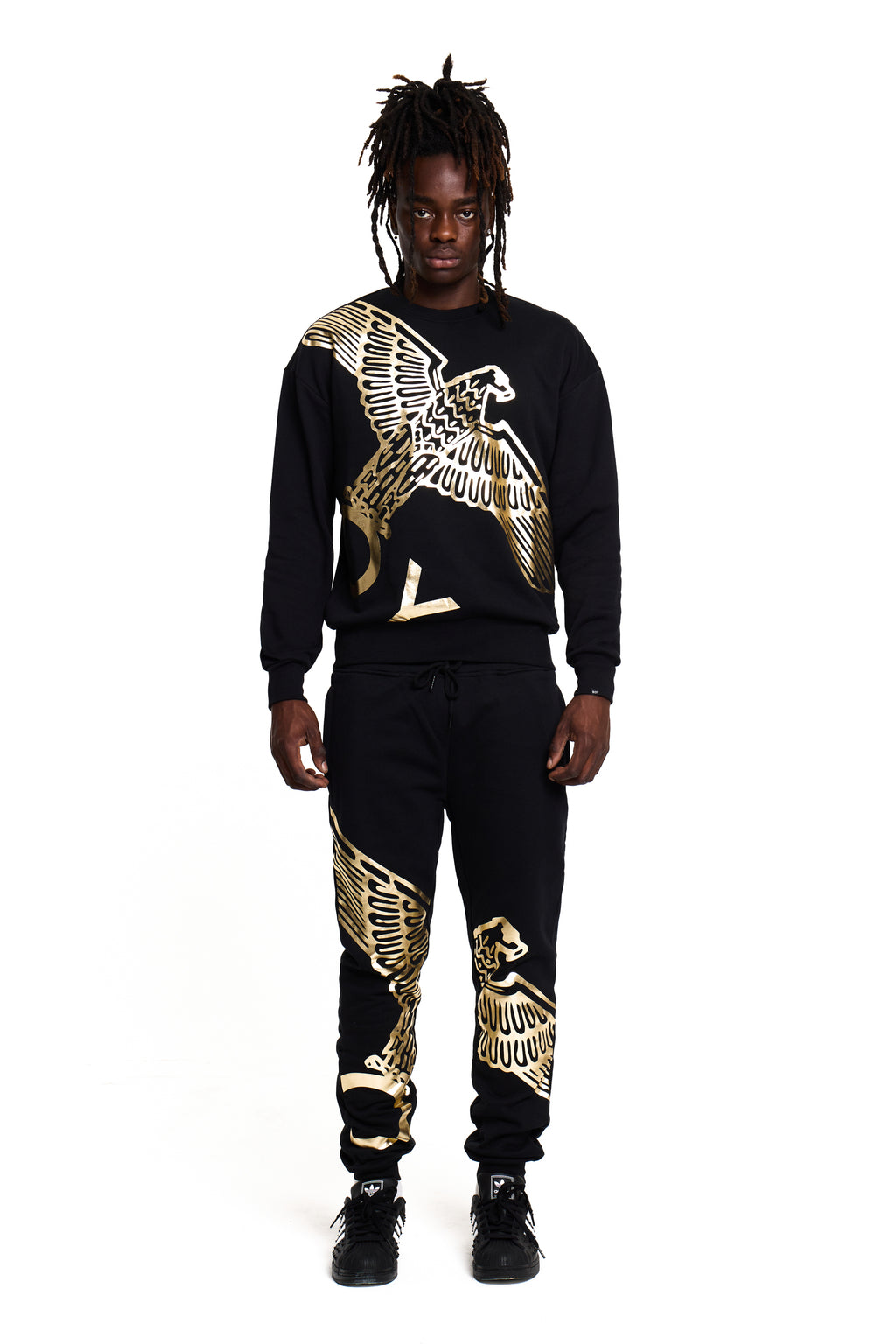 Model wearing a black and gold BOY London tracksuit with eagle designs on a white background