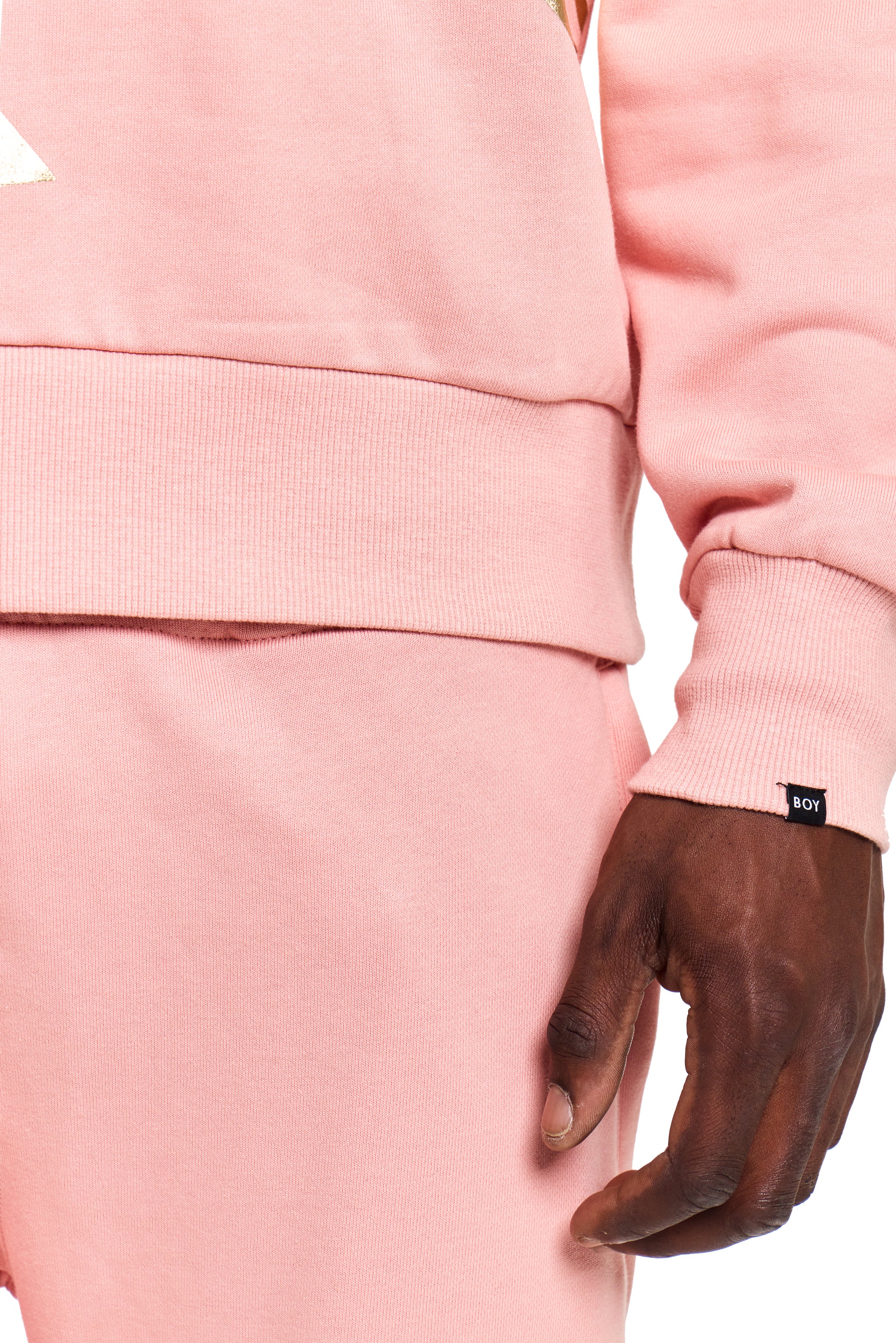 Person wearing a pink BOY London tracksuit with a leather glove on a white background