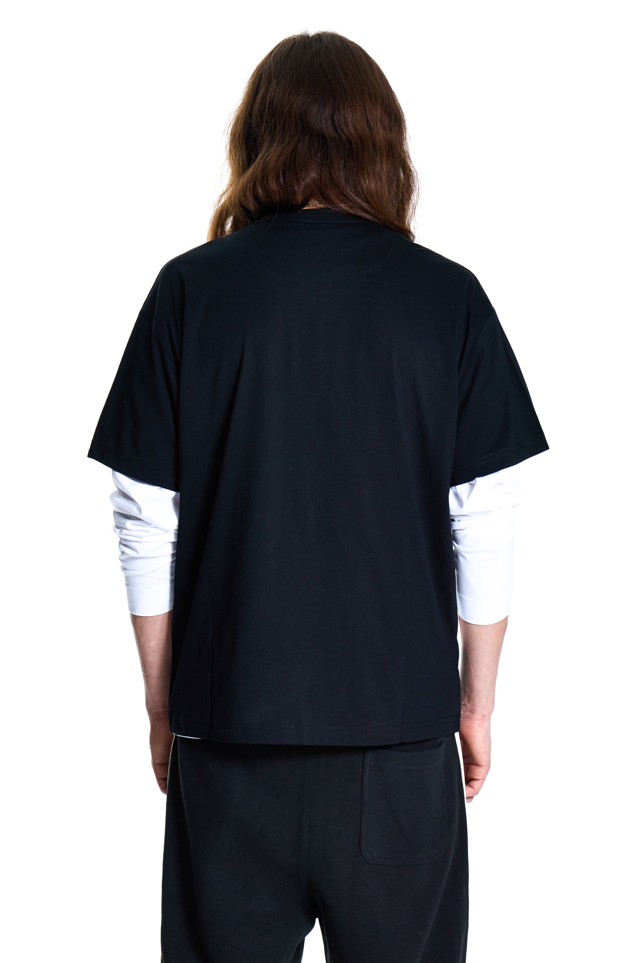 Person wearing a black scrub top with white sleeves on a white background