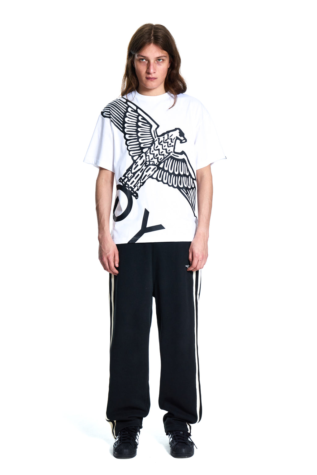 Person wearing a white t-shirt with an eagle design and black pants on a white background