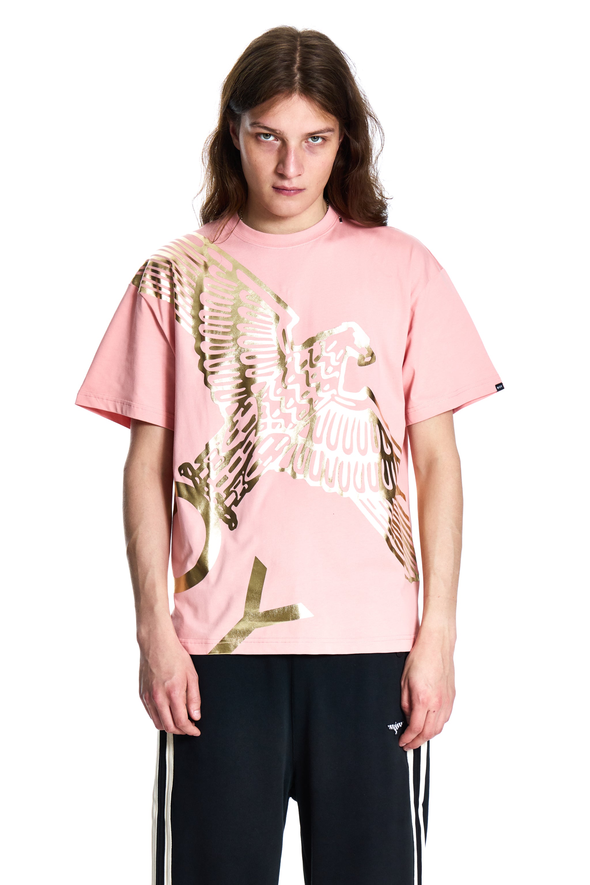 Person wearing a pink t-shirt with a gold eagle design on a white background
