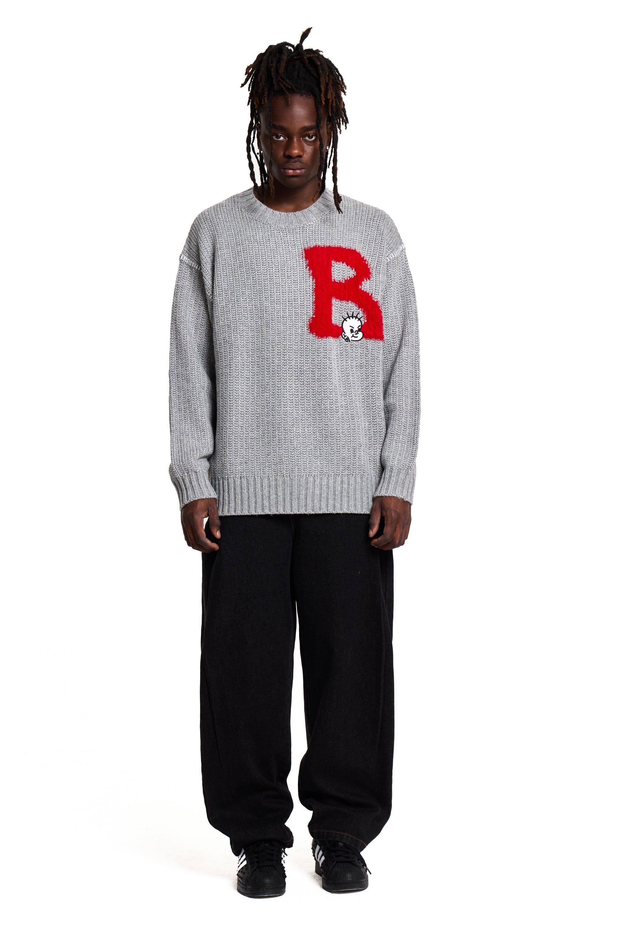 Person wearing a gray Boy London sweater with a red 'B' logo on a white background