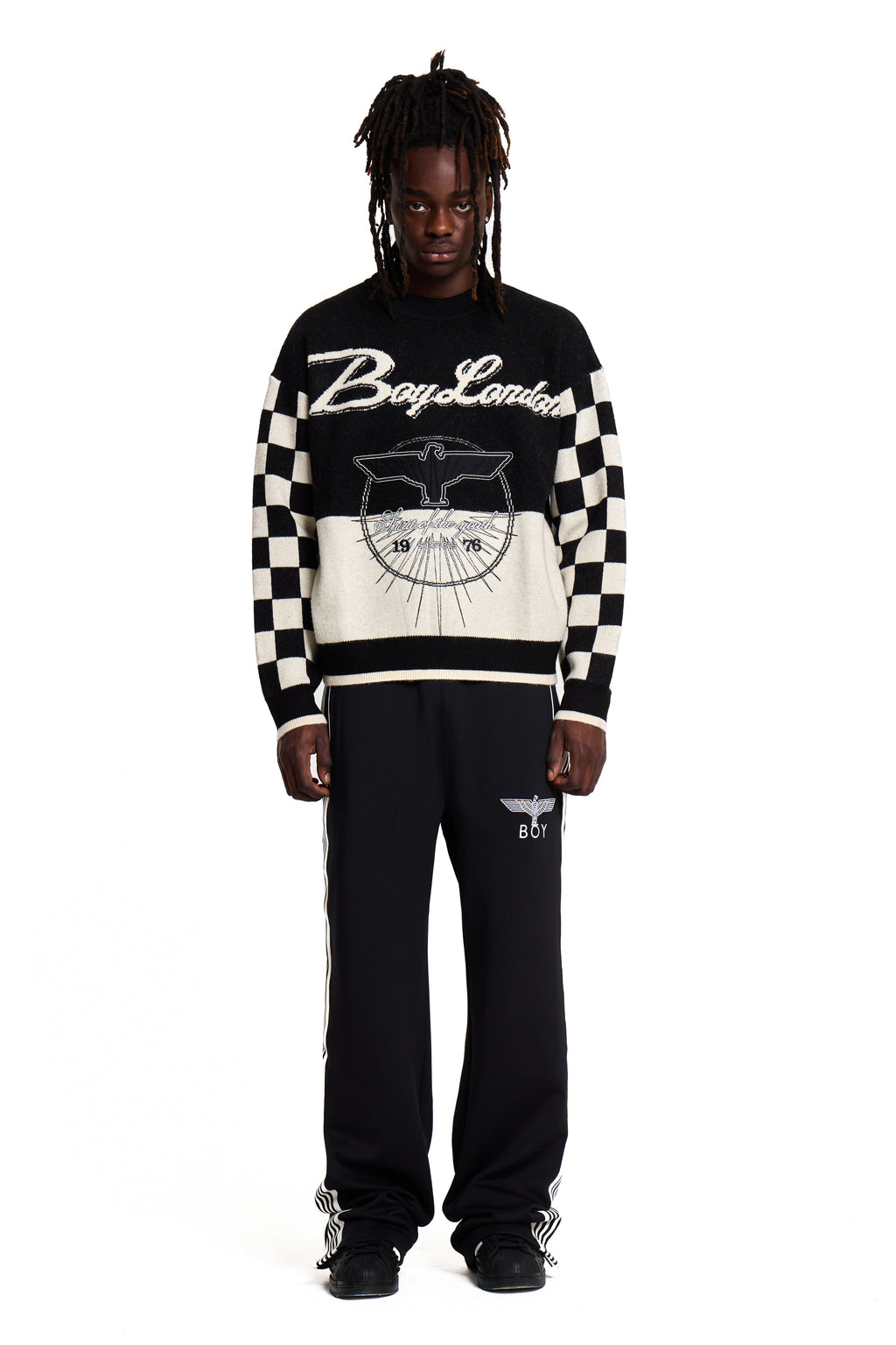 Person wearing a black and white Boy London checkered sweater with visible branding on a white background