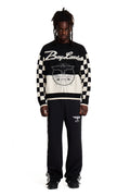 Person wearing a black and white Boy London checkered sweater with visible branding on a white background