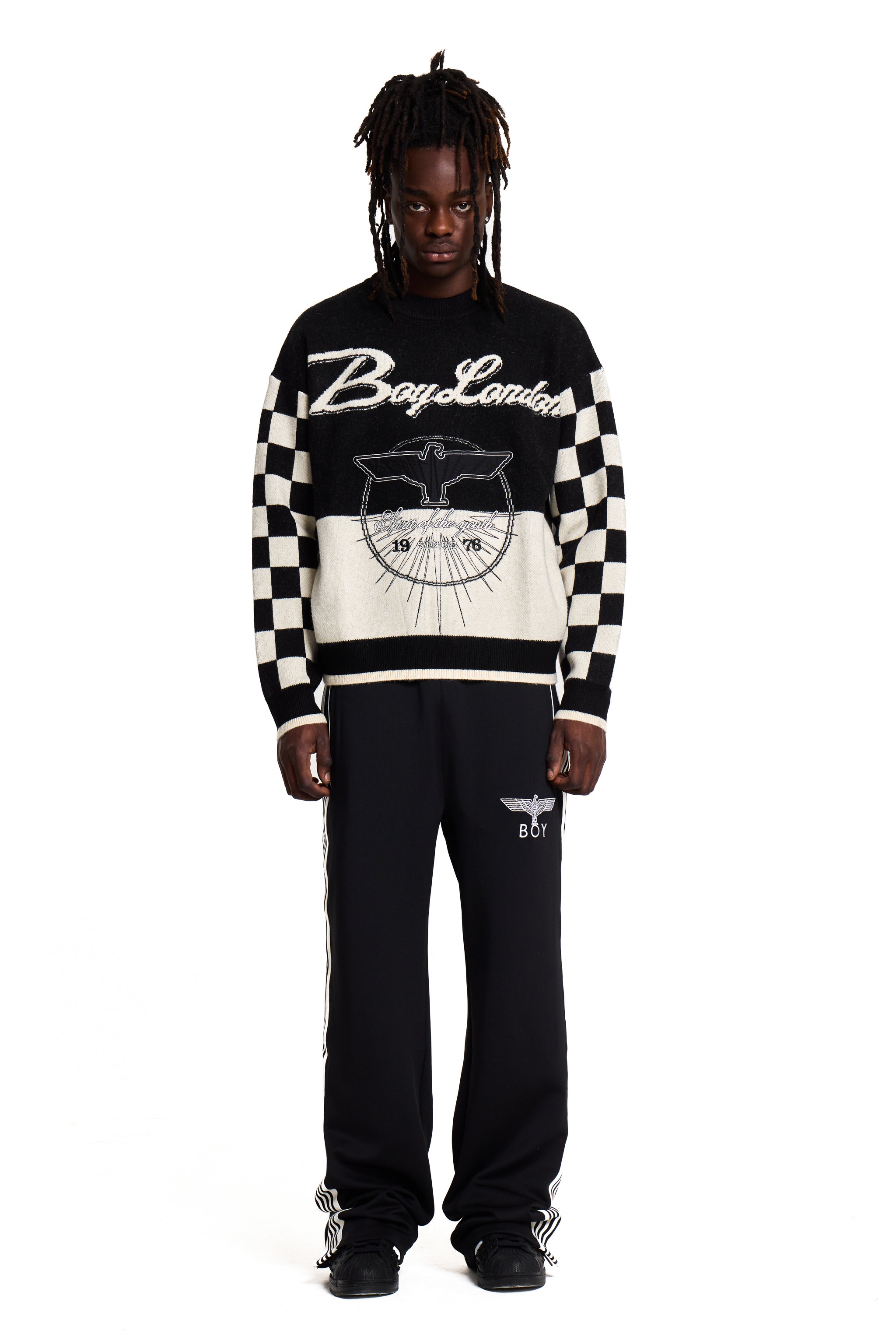 Person wearing a black and white Boy London checkered sweater with visible branding on a white background