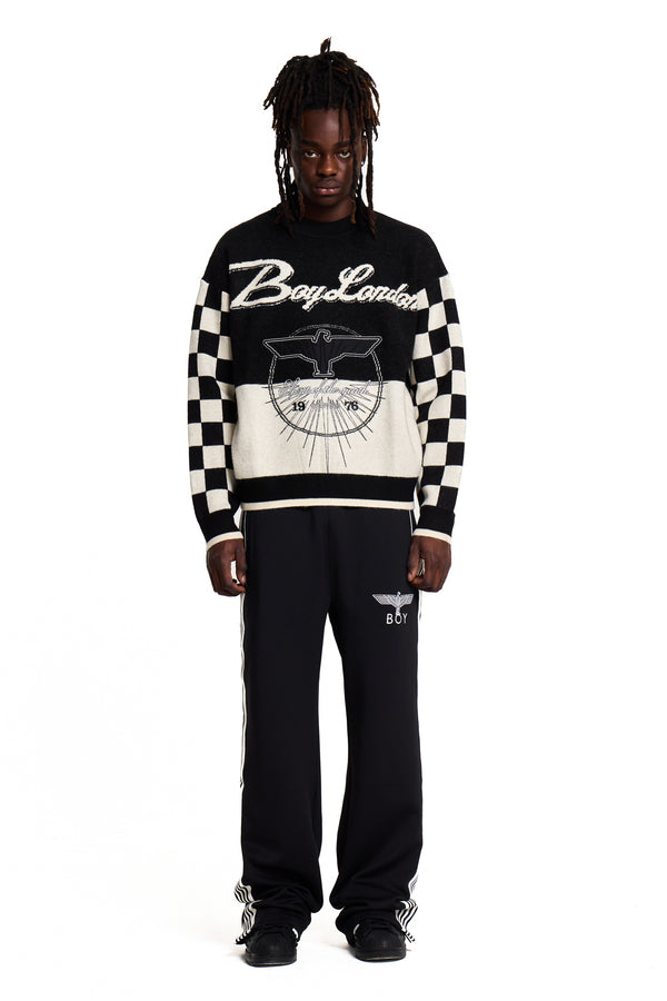 Person wearing a black and white Boy London checkered sweater with visible branding on a white background
