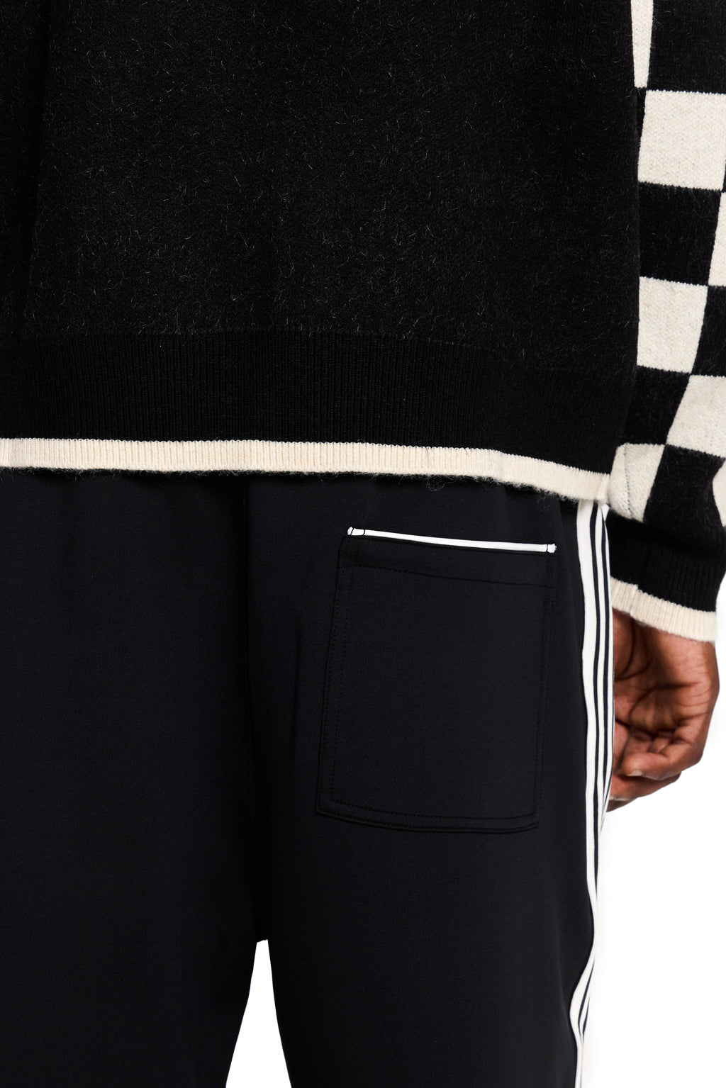 Black pants with white stripes and a checkered sleeve in the background