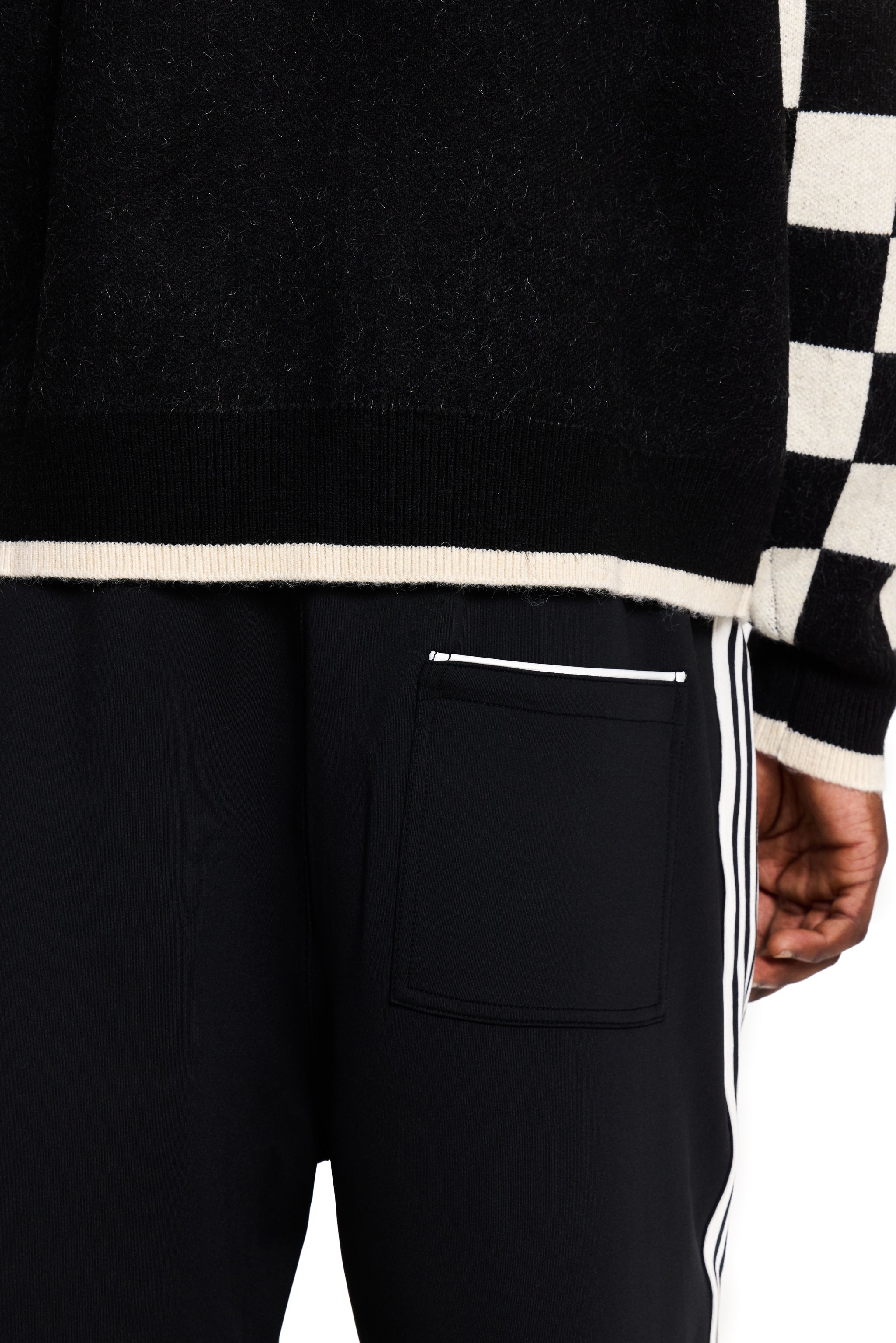 Black pants with white stripes and a checkered sleeve in the background