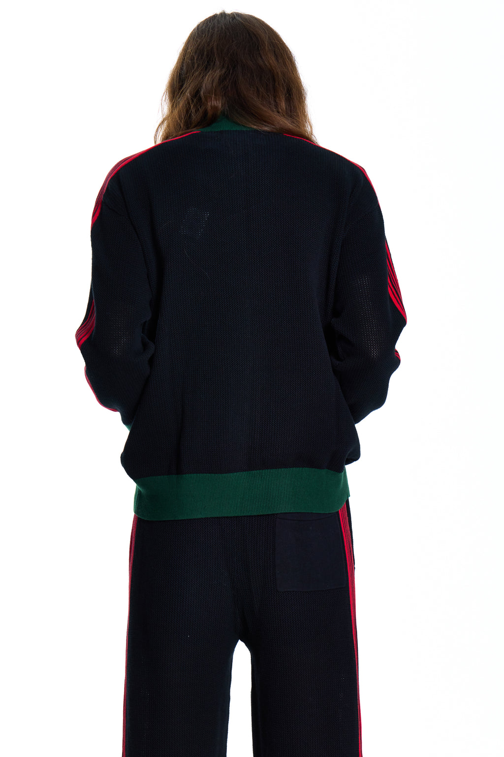 Person wearing a black tracksuit with green and red accents on a white background