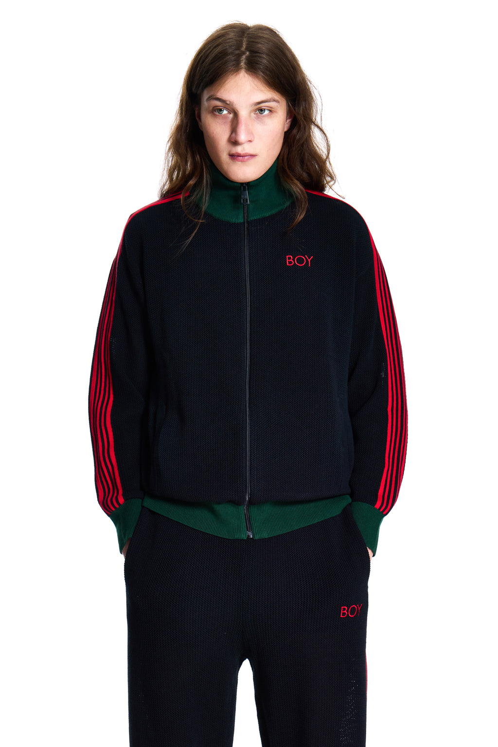 Person wearing a black tracksuit with red and green accents on a white background