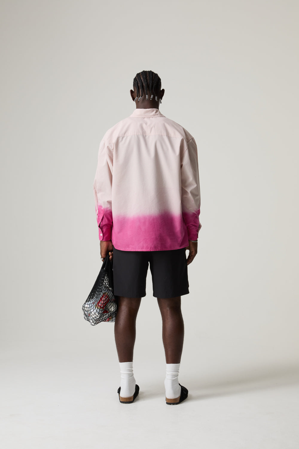 Model wearing a pink and white BOY LONDON shirt with black shorts on a plain background