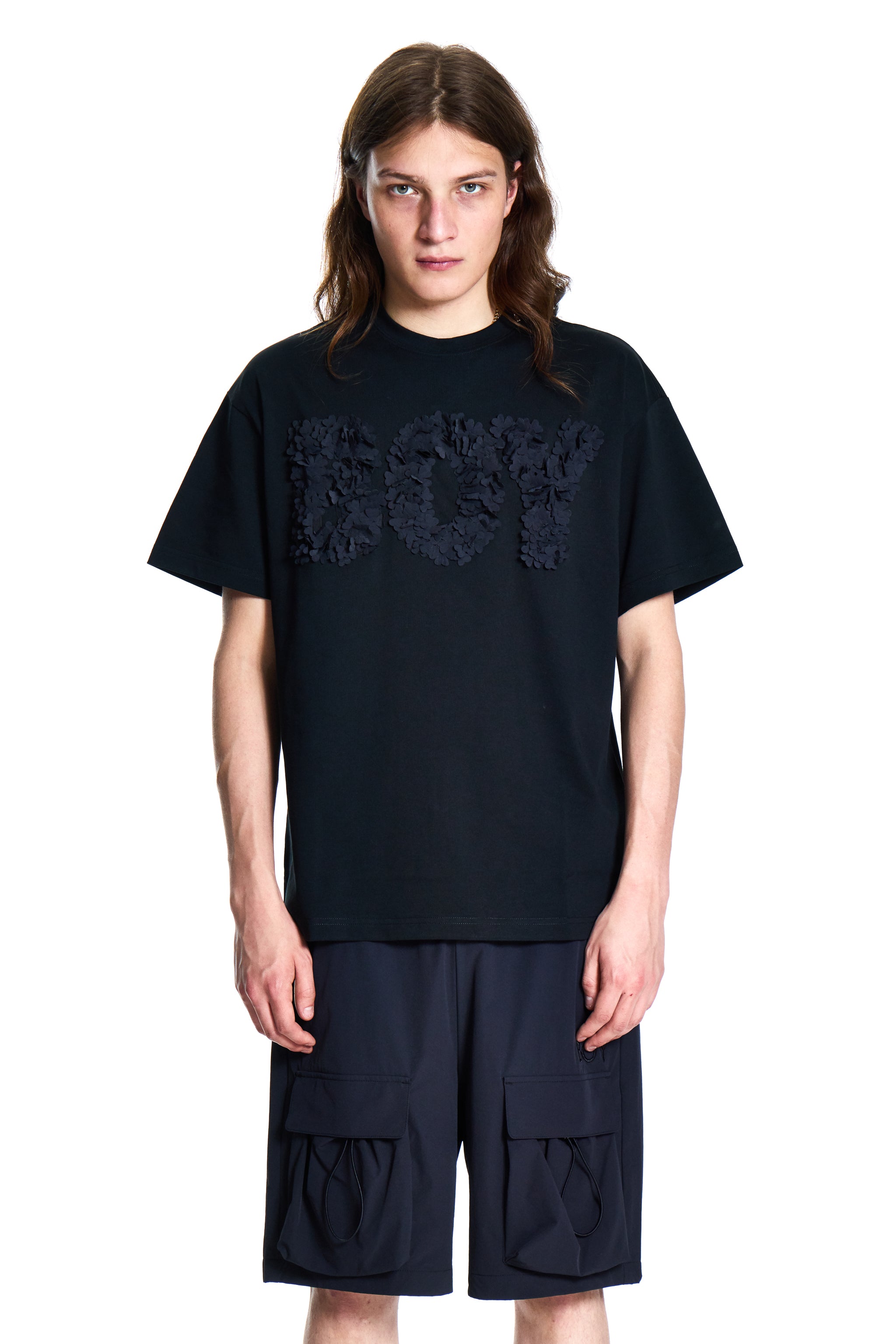 Person wearing a black BOY London t-shirt and shorts set on a white background