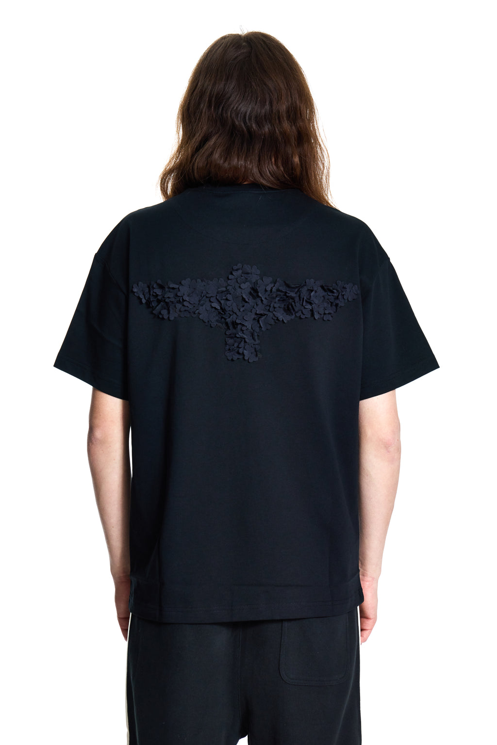 Person wearing a black t-shirt with BOY London lace details on the back against a white background