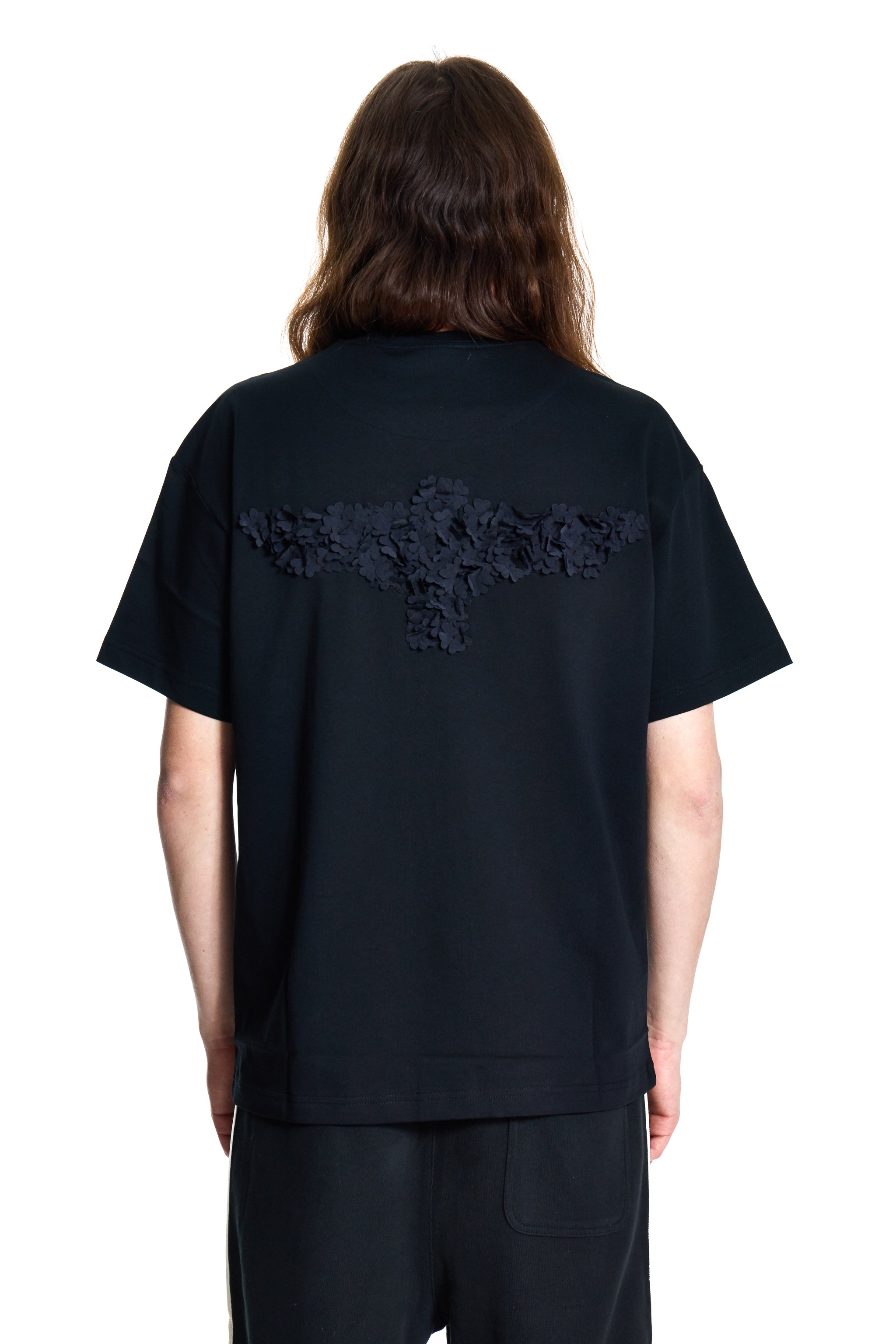 Person wearing a black t-shirt with BOY London lace details on the back against a white background