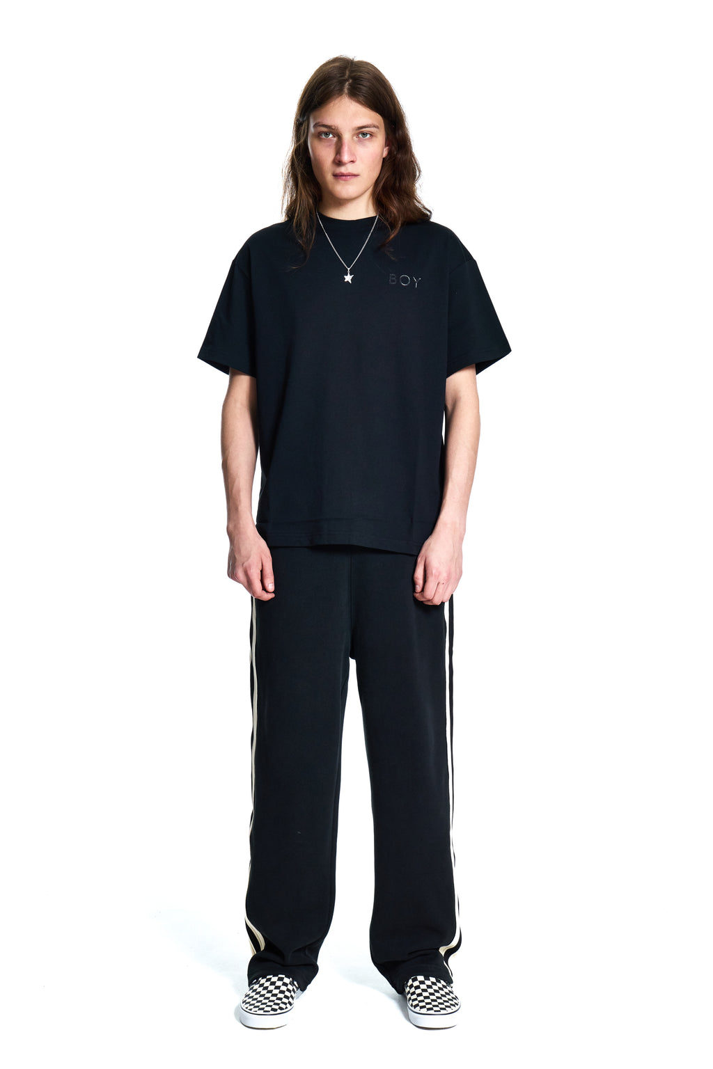 Person wearing a black BOY London t-shirt and pants with white stripes on a white background