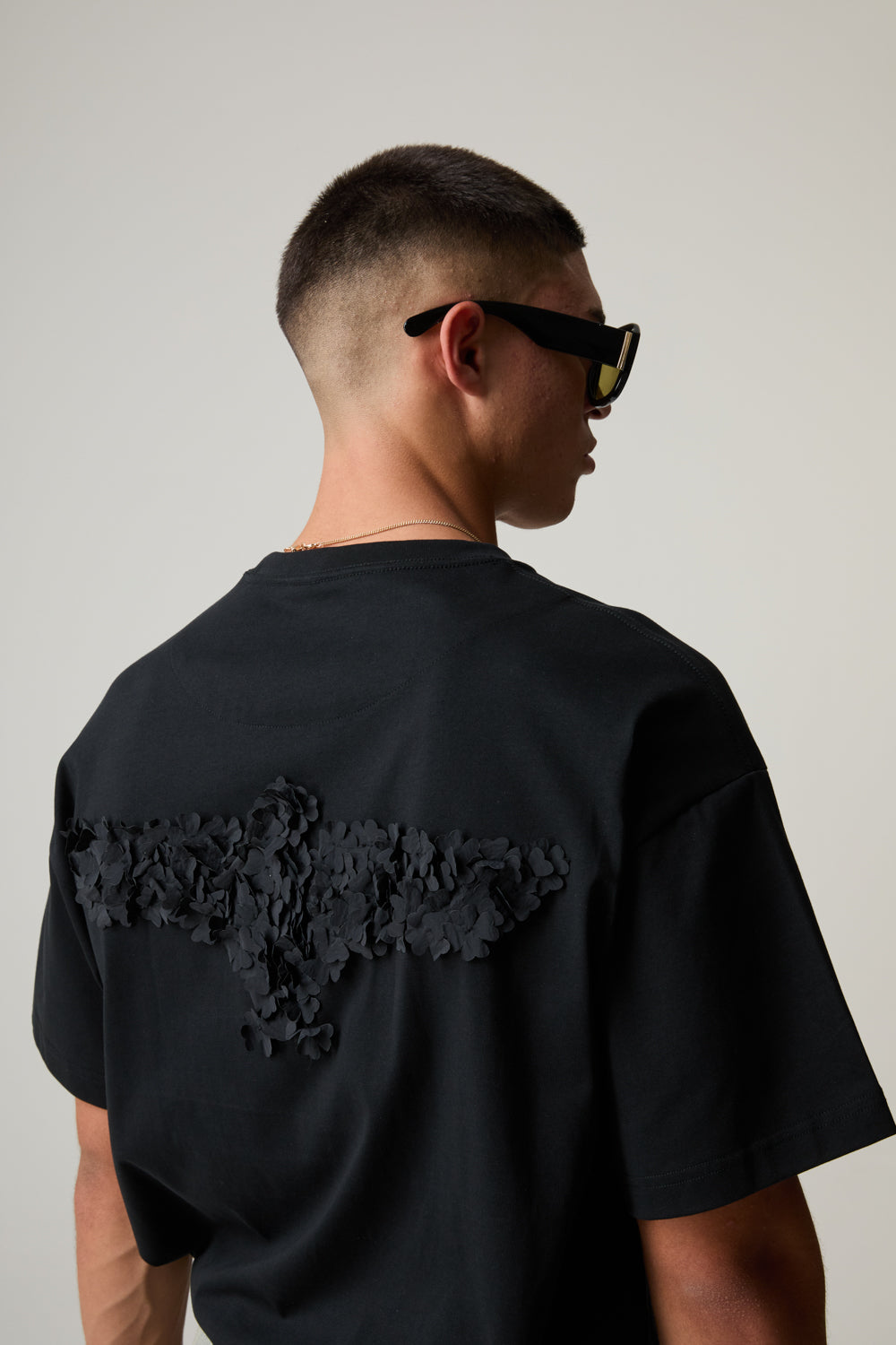 Model wearing a BOY LONDON black t-shirt with a unique design on the back against a plain background