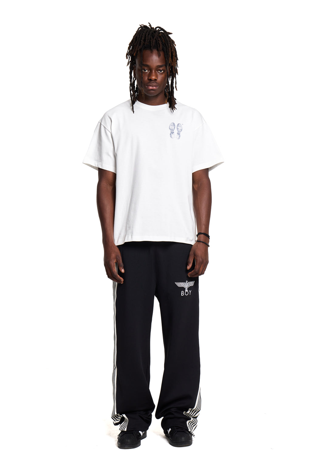 Person wearing a Boy London white t-shirt and black pants with a logo on a white background