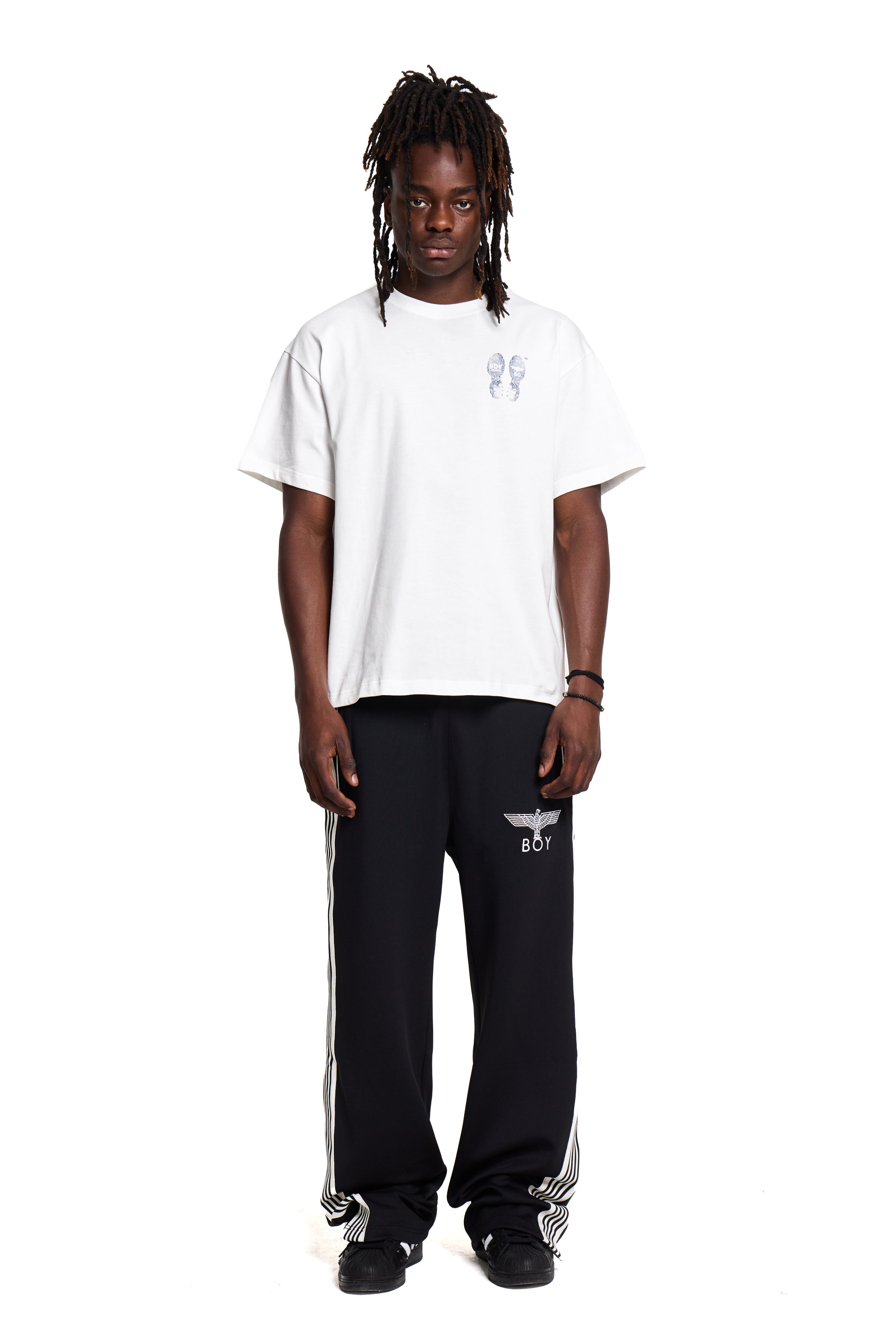 Person wearing a Boy London white t-shirt and black pants with a logo on a white background