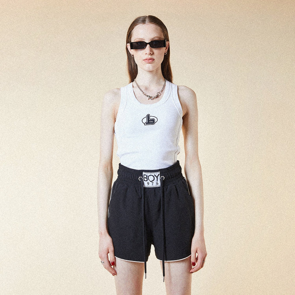 Model wearing BOY London white tank top with a black logo on a white background