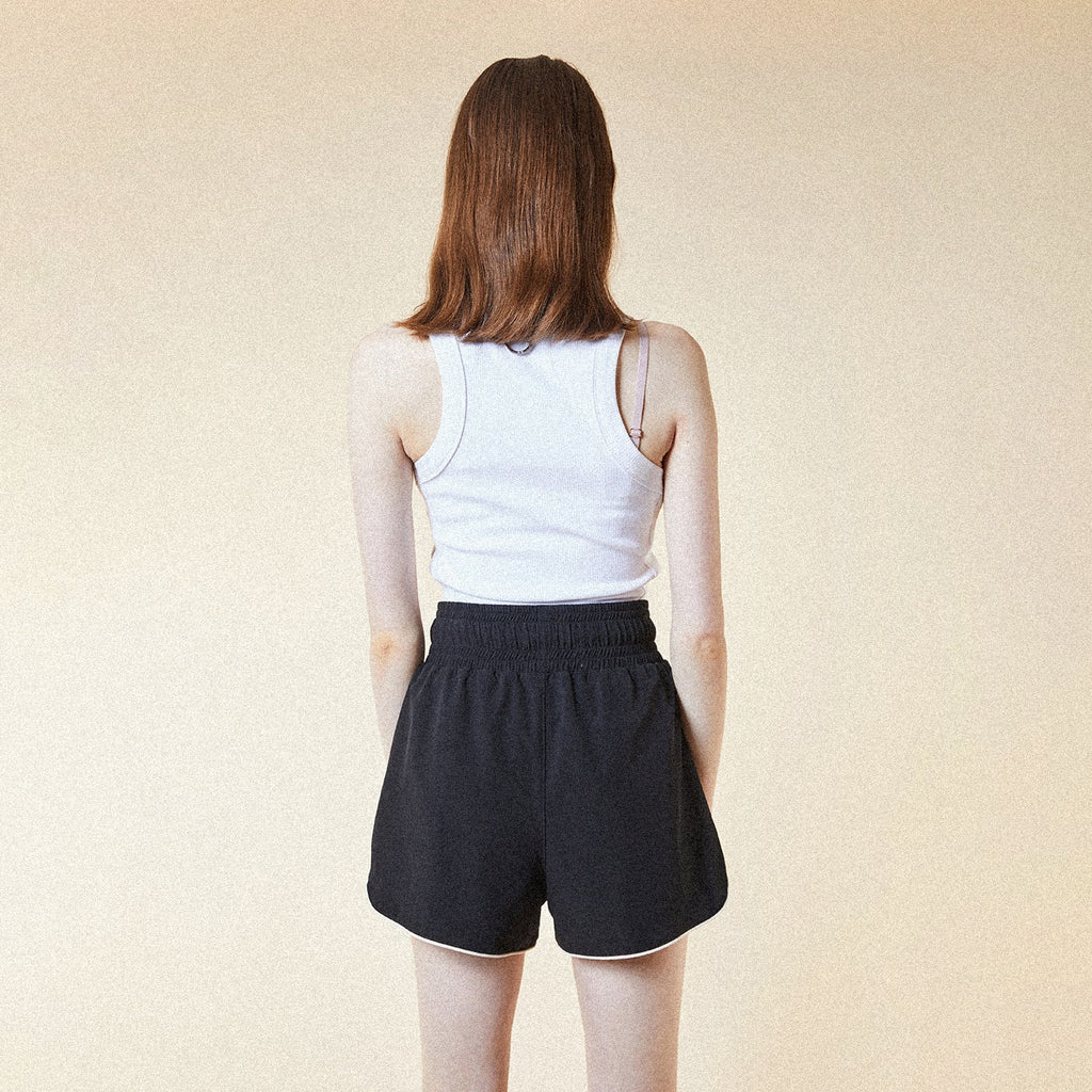 Model wearing BOY London white tank top with a black logo on a white background