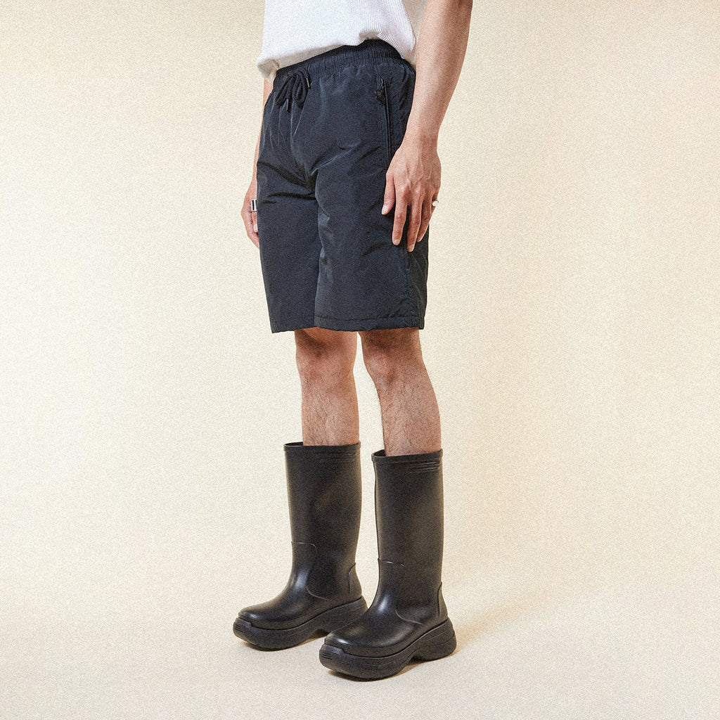 Model wearing BOY London shorts on plain background 
