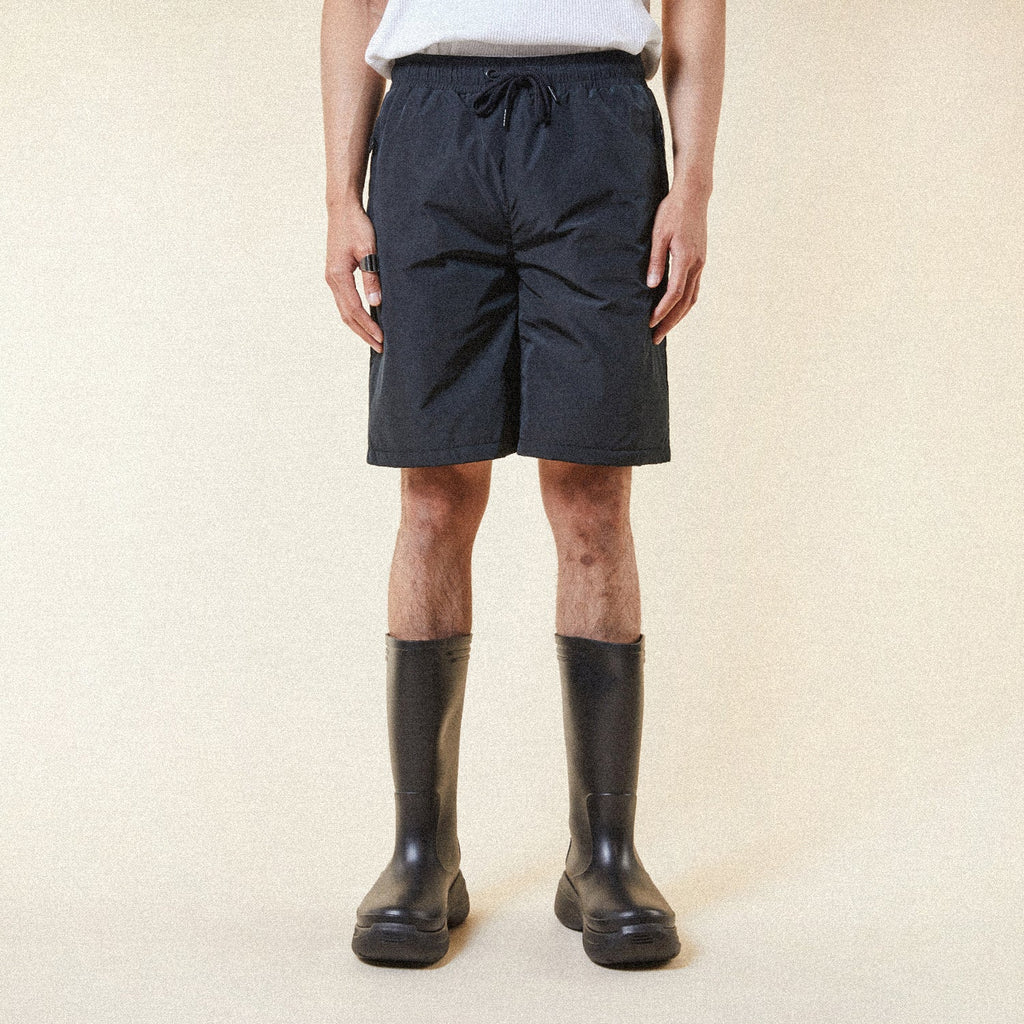 Model wearing BOY London shorts on plain background 