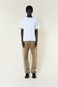Person wearing a BOY London white t-shirt and beige pants on a plain background