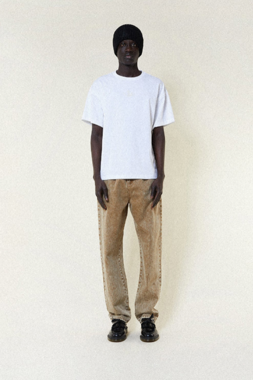 Person wearing a BOY London white t-shirt and beige pants on a plain background
