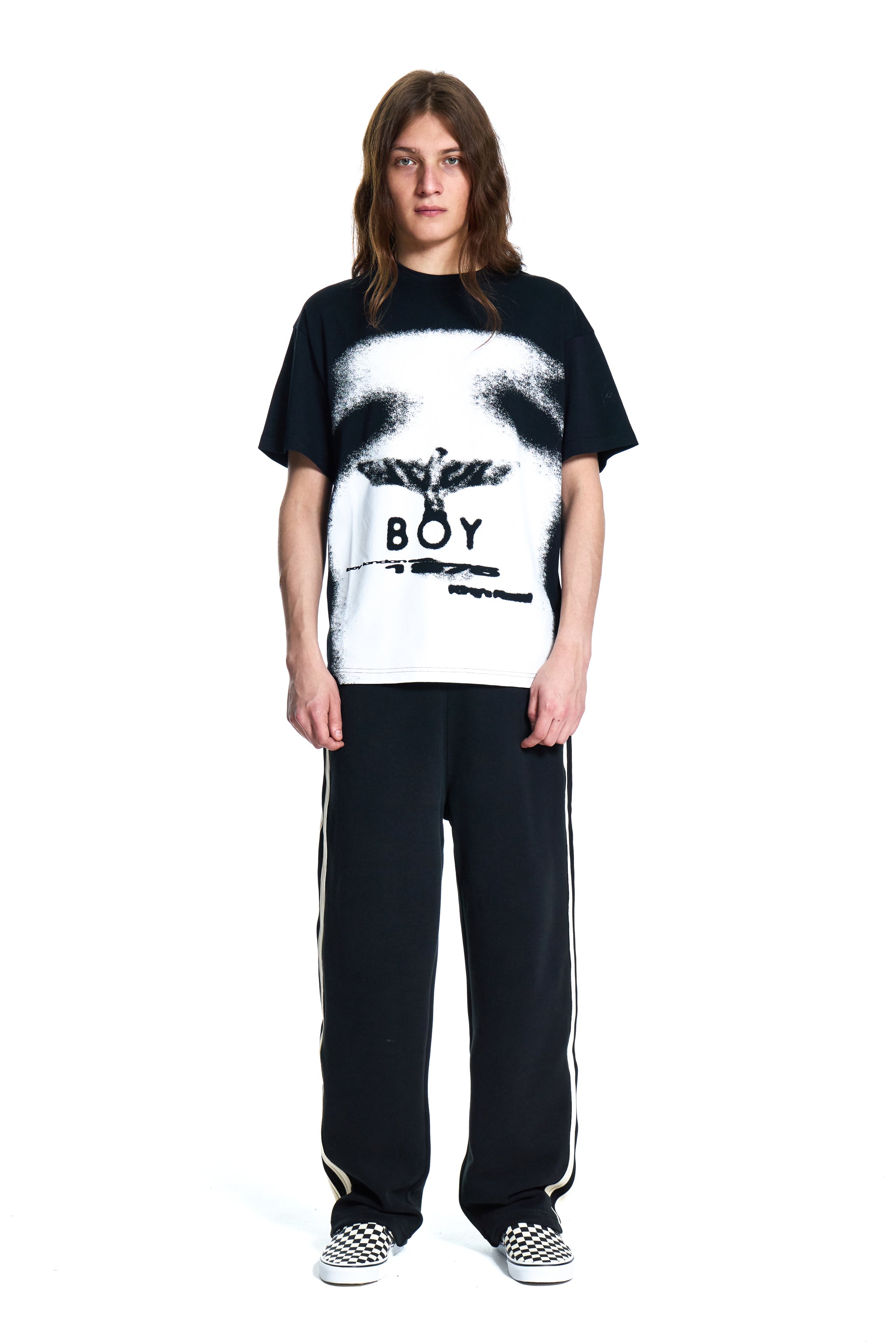Person wearing a BOY London black t-shirt with a graphic design and text, standing against a white background