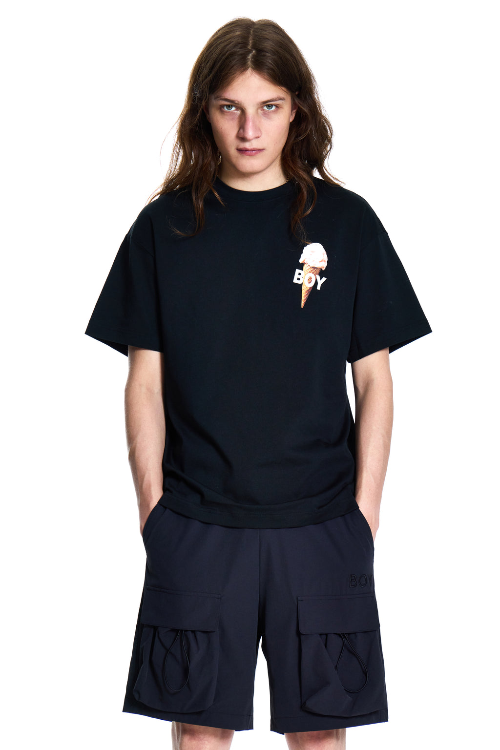 Person wearing a black Boy London t-shirt with an ice cream cone logo and cargo shorts on a white background