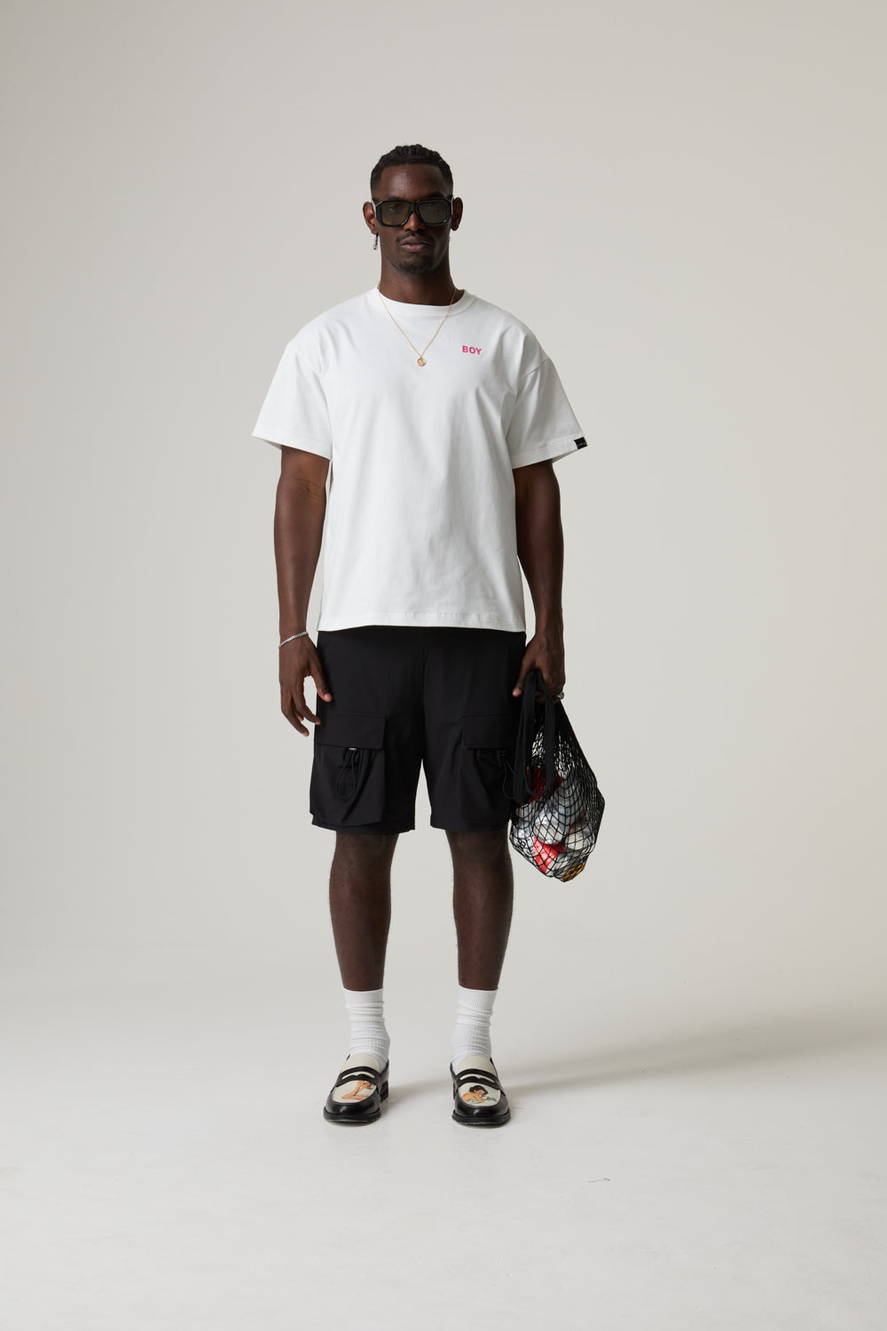 Model wearing a BOY LONDON white t-shirt and black cargo shorts on a plain background