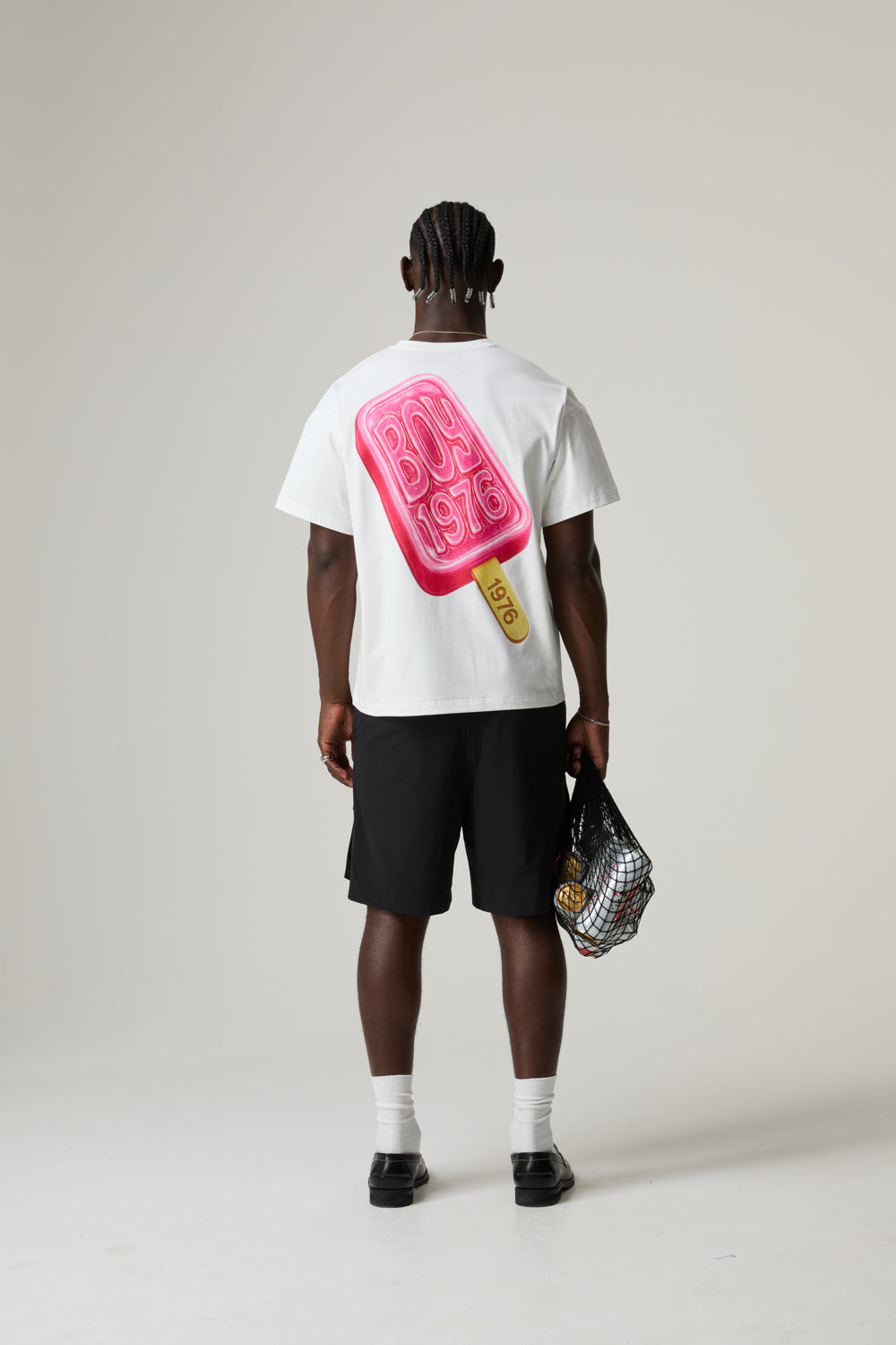 Model wearing a white BOY LONDON t-shirt with a pink ice lolly cone graphic on the back, standing against a plain background.