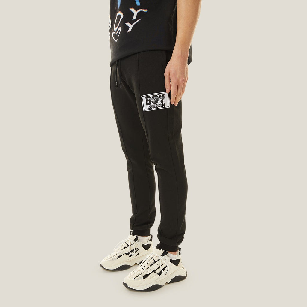 Model wearing boy london joggers on plain background
