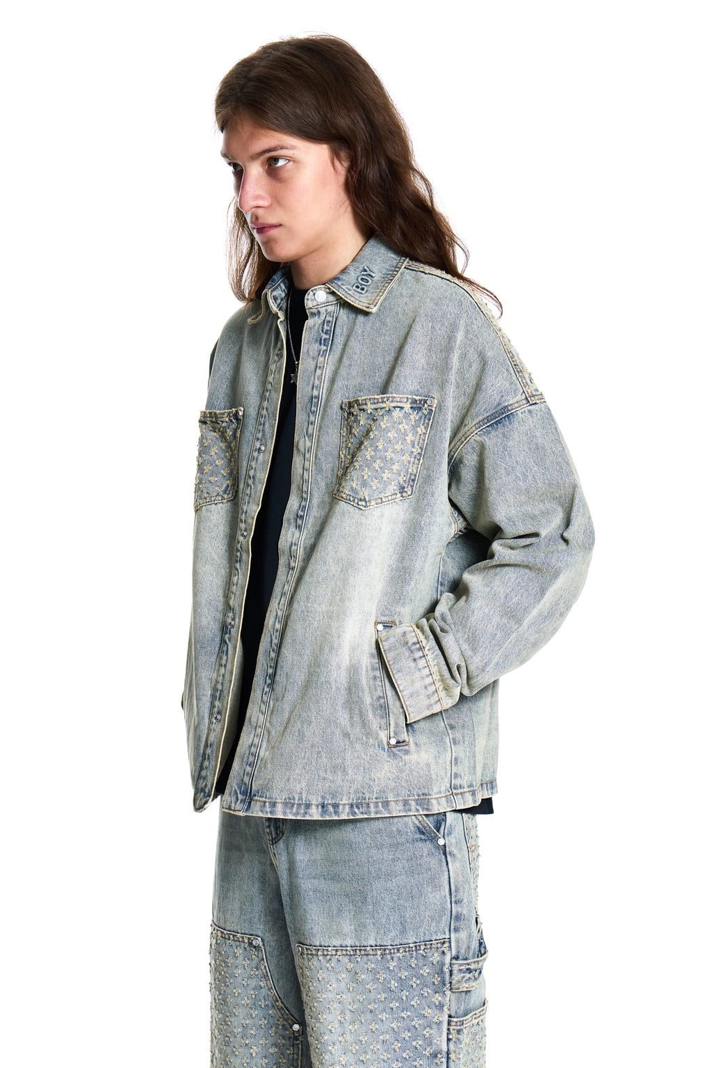 Person wearing a light blue denim jacket and pants on a white background