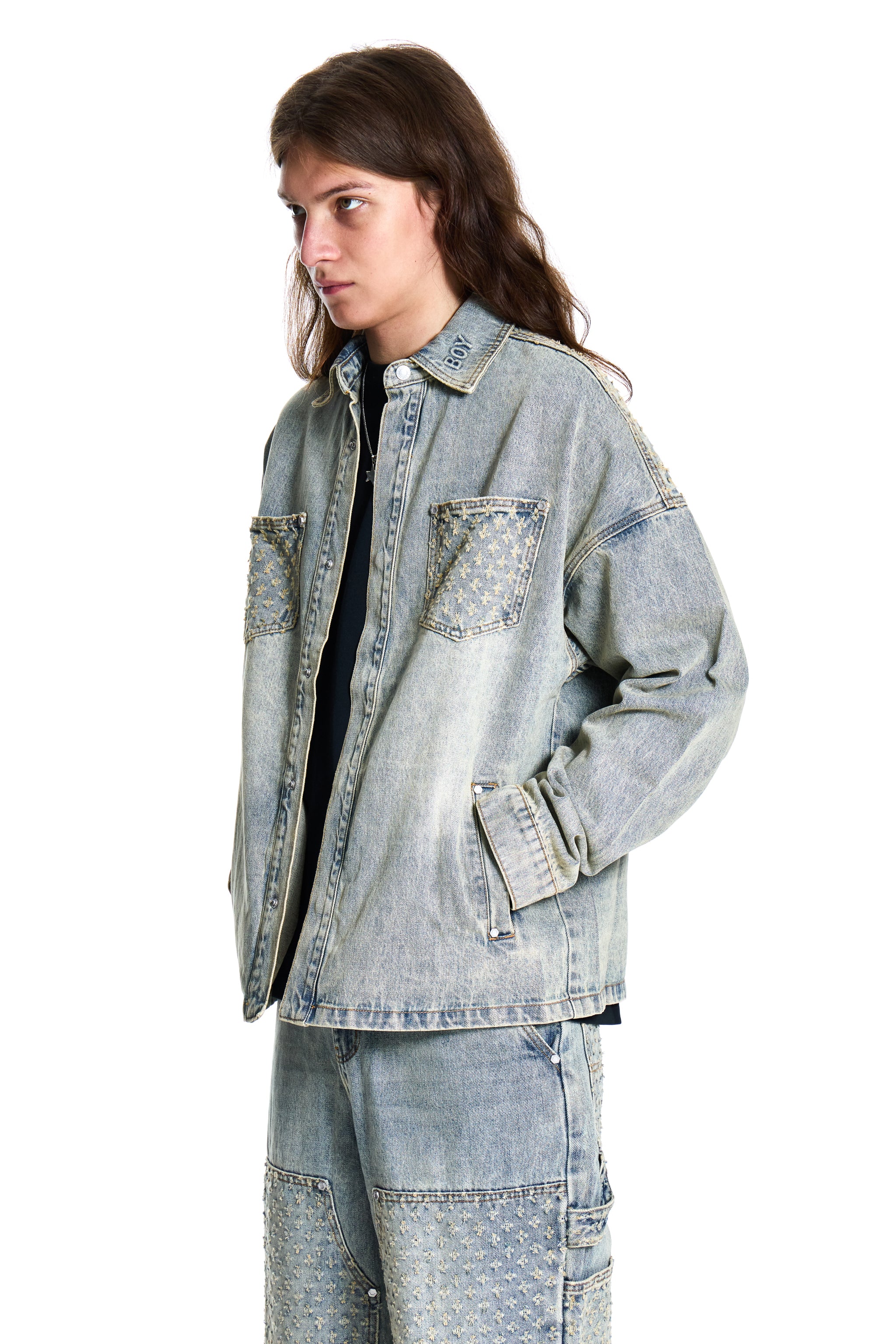 Person wearing a light blue denim jacket and pants on a white background