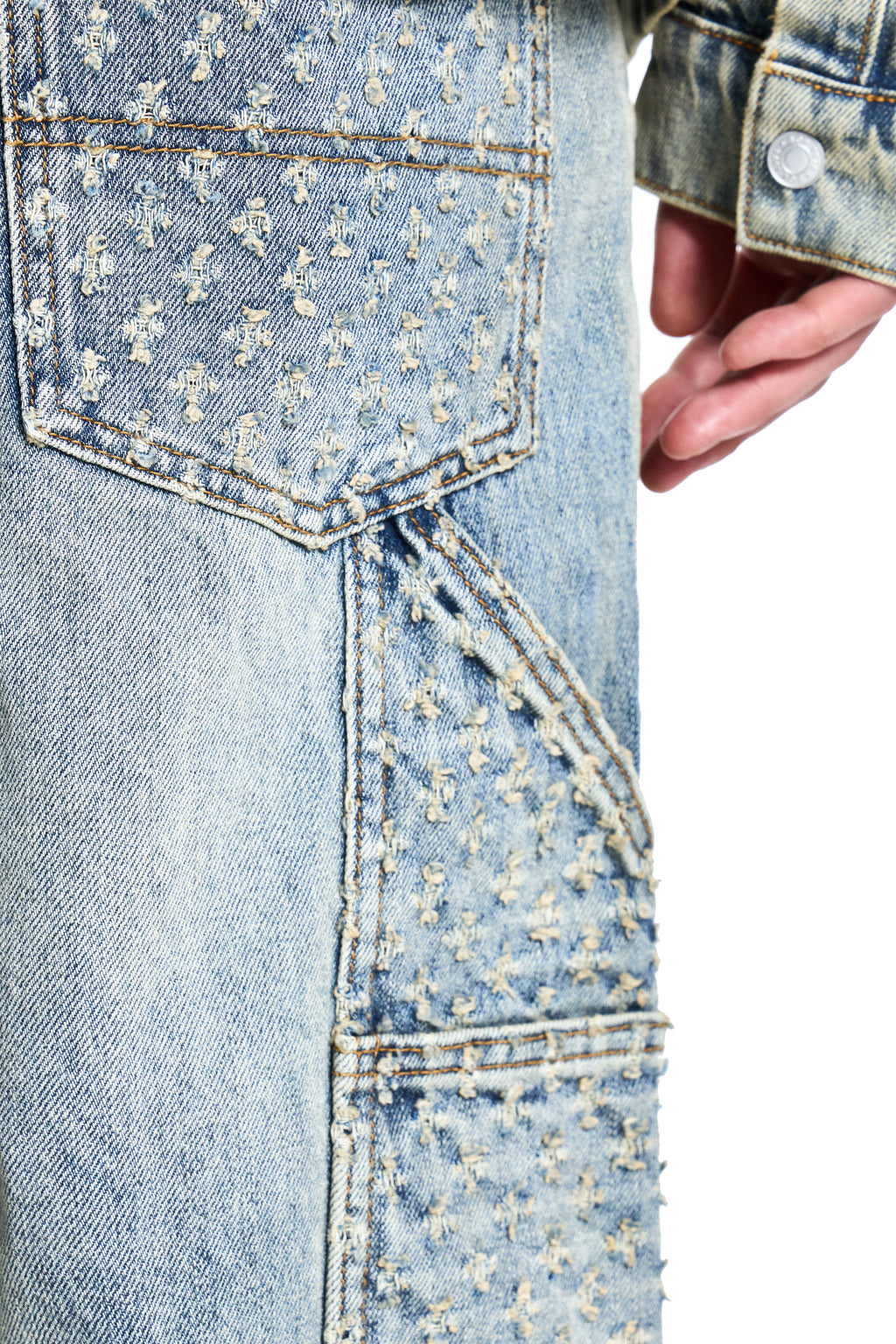 Close-up of a light blue BOY London denim jacket with floral patterns on the pocket and stitching.