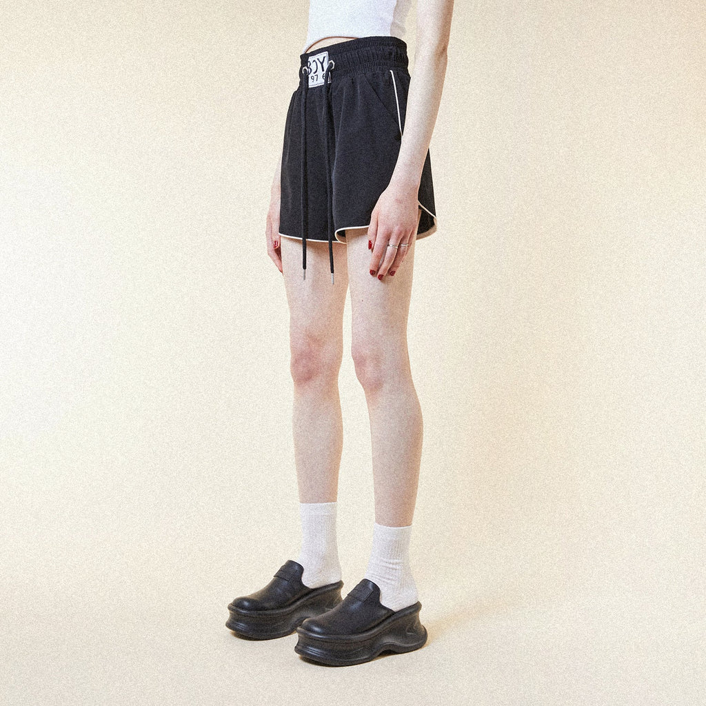 Model wearing BOY London shorts on plain background