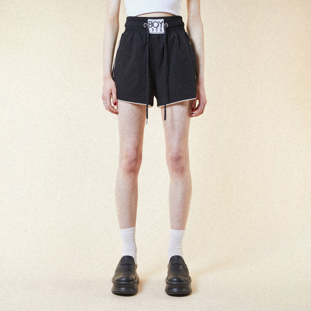 Model wearing BOY London shorts on plain background