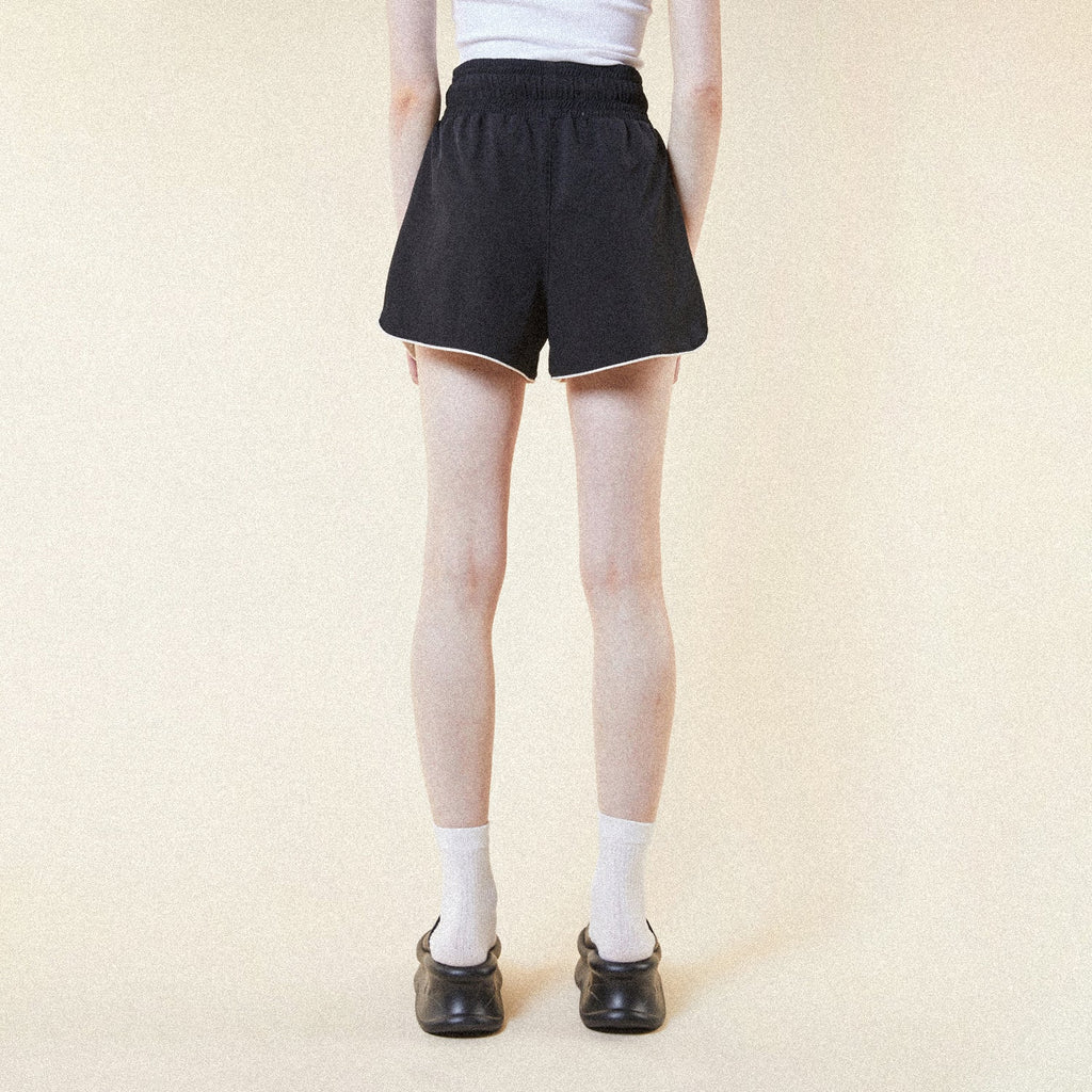 Model wearing BOY London shorts on plain background